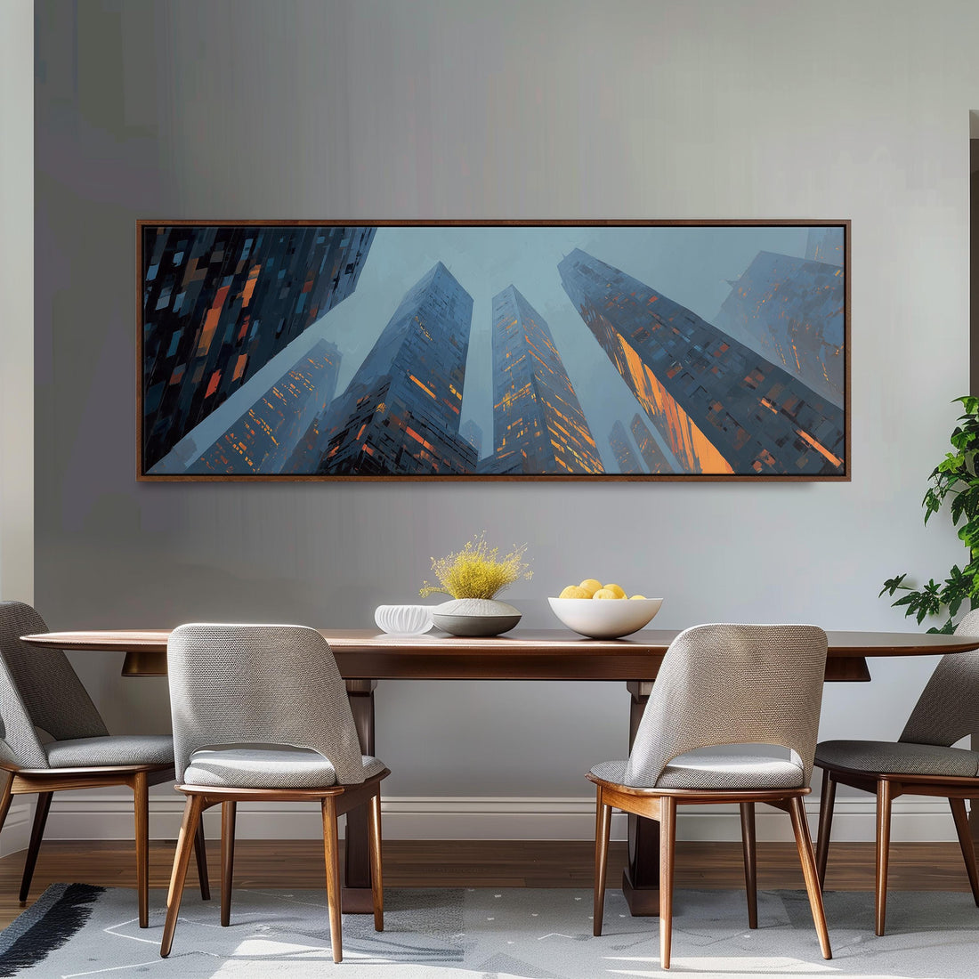 a modern dining room with a large painting of tall buildings on the wall above a wooden dining table with four chairs. The painting has a blue and orange color scheme, creating a striking contrast against the gray wall. The dining table is set with a bowl of fruit and a vase of flowers, adding a touch of elegance to the space.