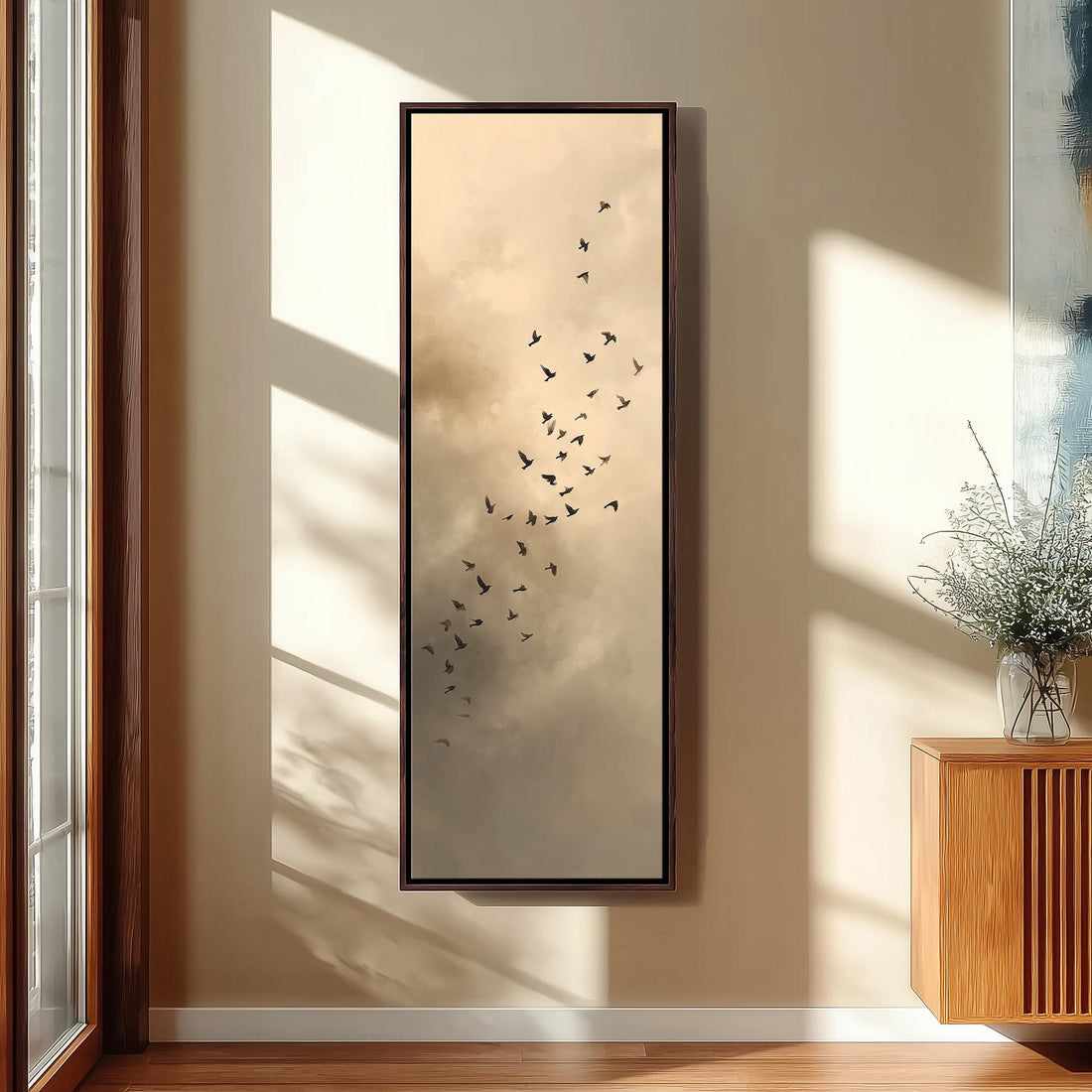 a serene bedroom scene with a large window, a white bed, a woven ottoman, and a framed picture of birds flying in the sky.