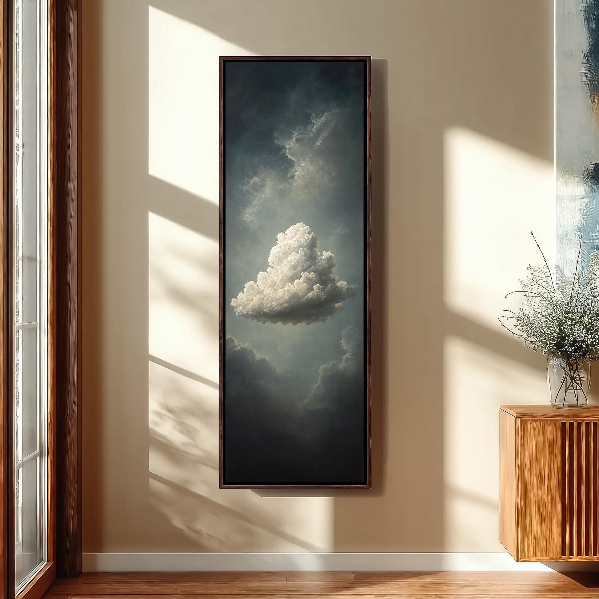 a large painting of a cloud hanging on a wall, with a wooden cabinet and a vase of flowers to the right of the painting.