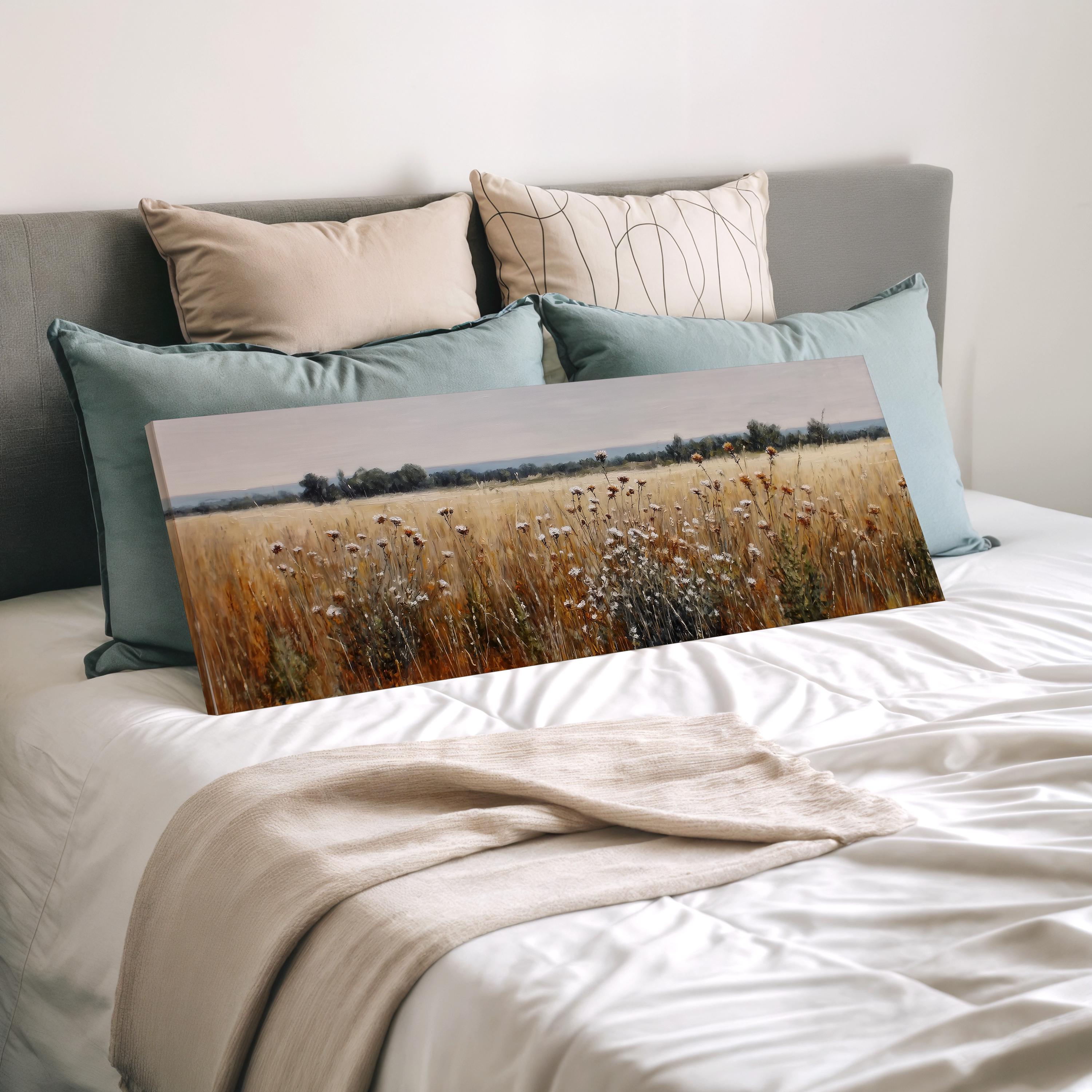 a bedroom with a bed and a large painting of a field of flowers on it. The painting is placed on the bed, which is covered with a white comforter and pillows.