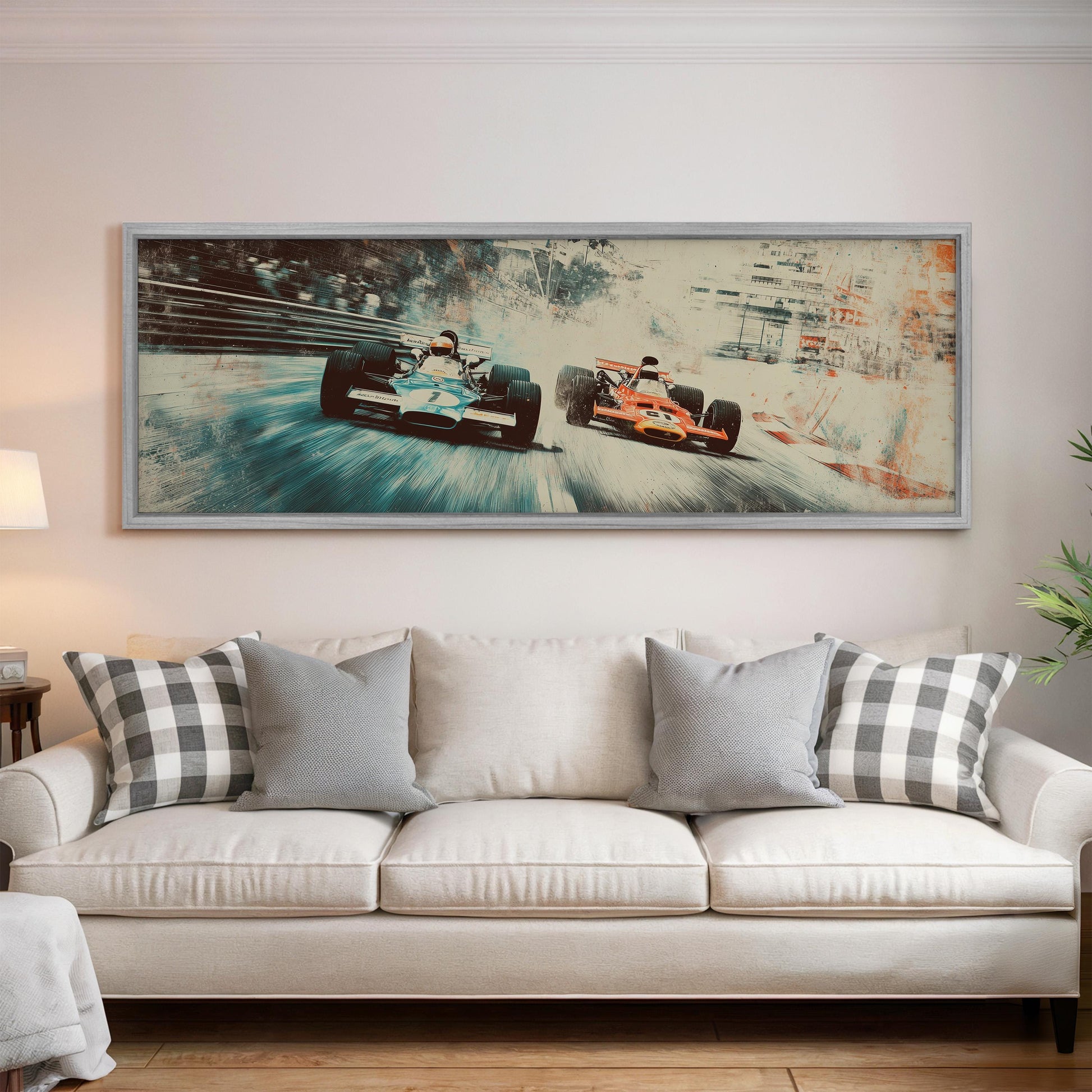 a large framed painting of two race cars speeding down a track, hanging on a wall above a white couch with patterned throw pillows.