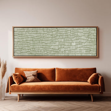 a large, rectangular, abstract painting hanging on a wall above a brown, plush couch with orange cushions.