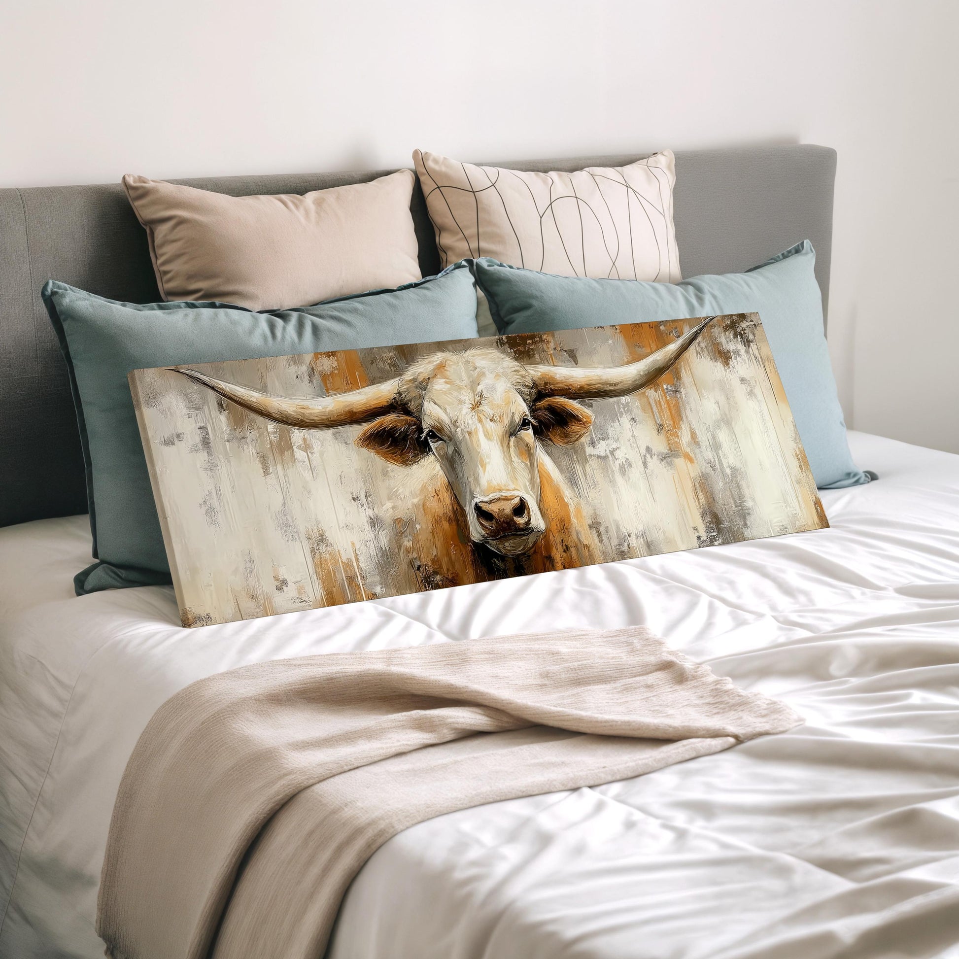 a large painting of a bull's head resting on a bed, surrounded by various pillows.