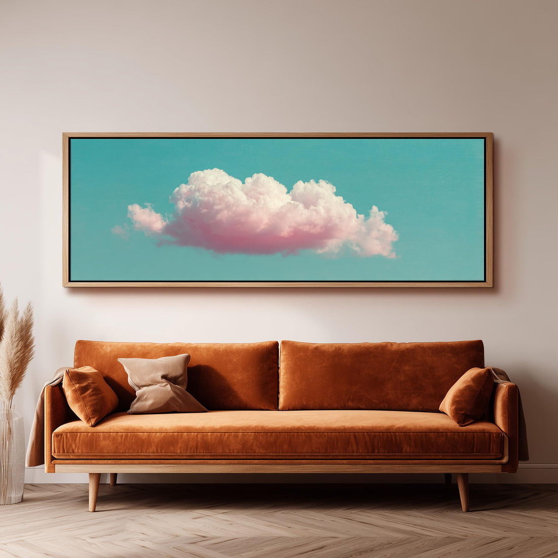 a large framed picture of a cloud with pink and white colors, hanging on a wall above a brown sofa.