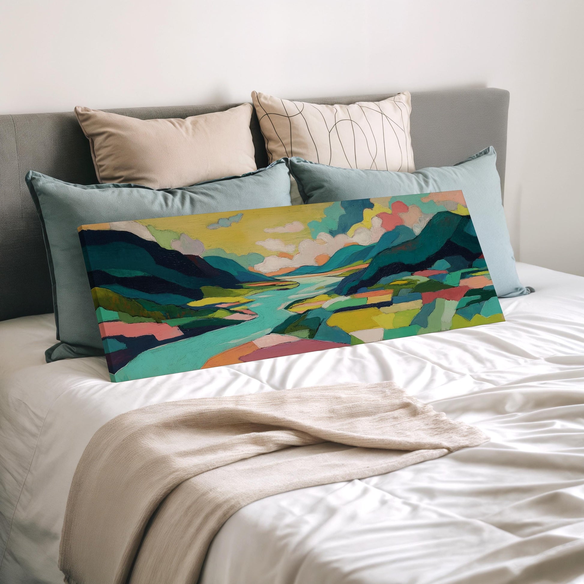 a bedroom with a bed and a colorful landscape painting displayed on it. The painting features a vibrant scene of mountains, a river, and a sky filled with clouds. The bed is covered with a white comforter and has several pillows arranged on it.