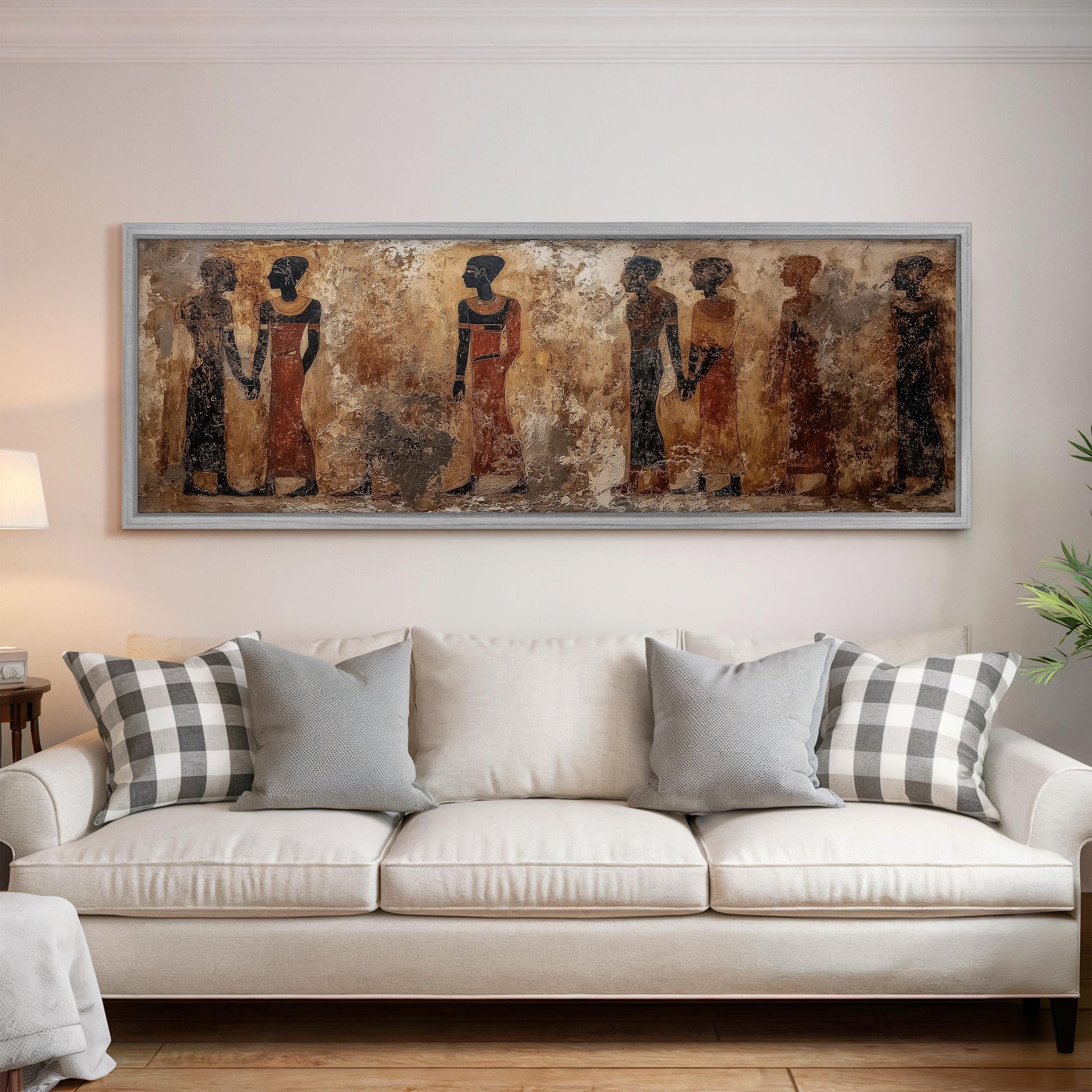 a large, framed painting of ancient Egyptian figures on the wall above a white sofa with gray and white plaid throw pillows.