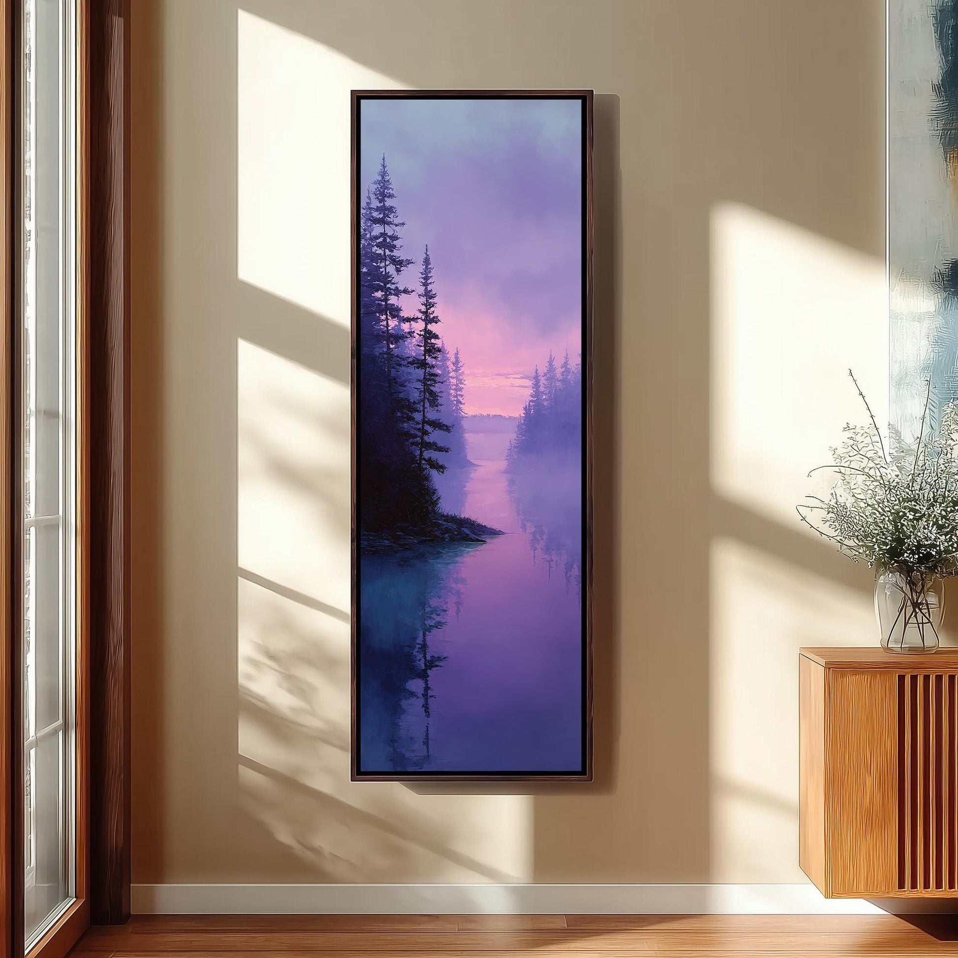 a large framed painting of a serene landscape with a forest and a body of water, hanging on a wall in a room with a wooden floor and a window.