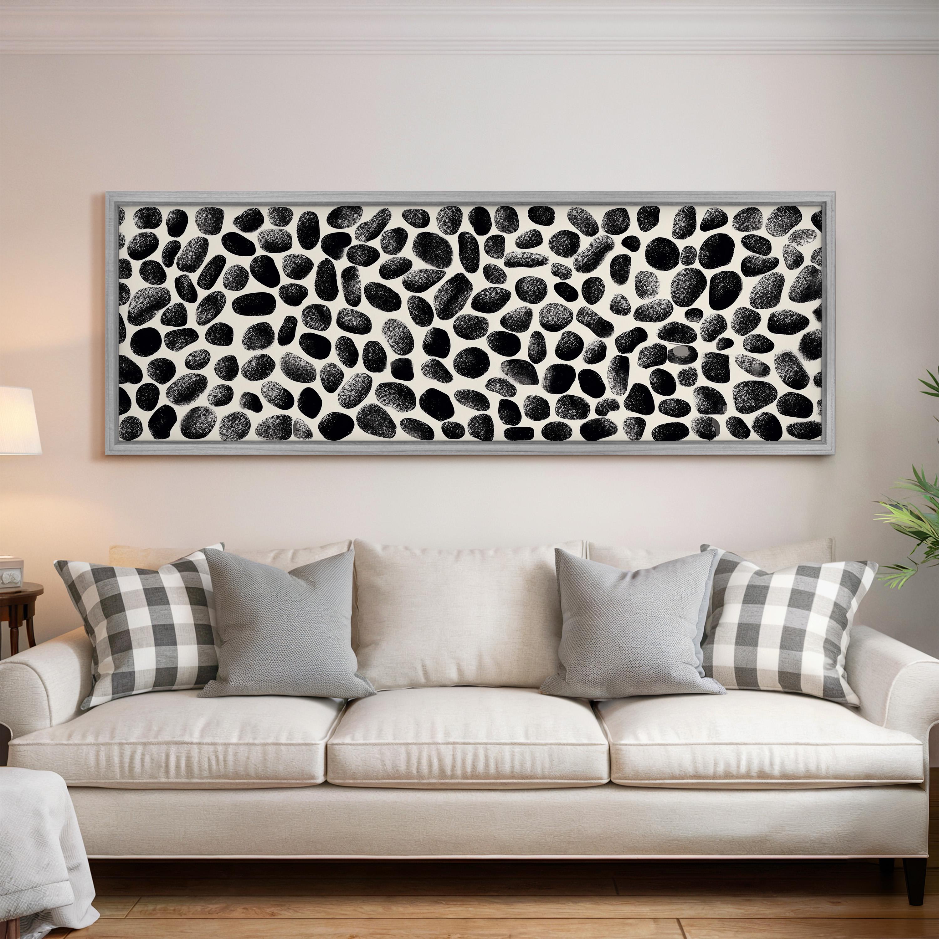 a living room with a white sofa adorned with gray and white plaid throw pillows. Above the sofa, there is a large black and white abstract painting hanging on the wall.