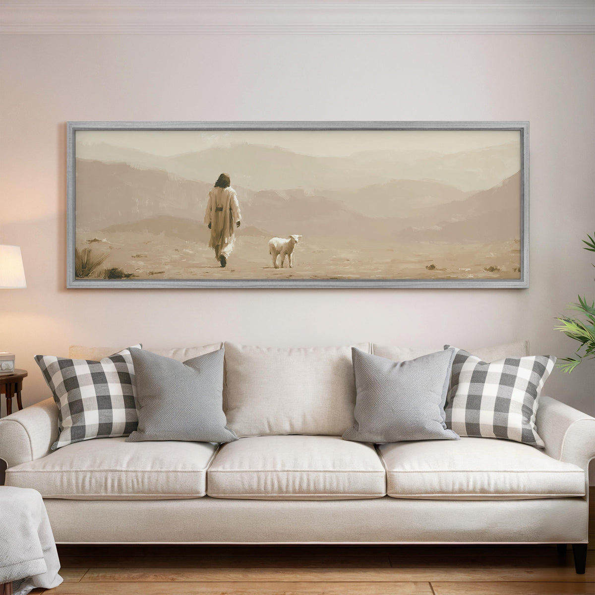 Jesus walking with a lamb through the desert panoramic canvas print above a white sofa in a bright living room