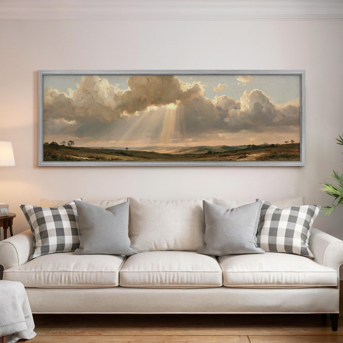 Sunbeams breaking through clouds over plains panoramic canvas print above a white sofa in a bright living room