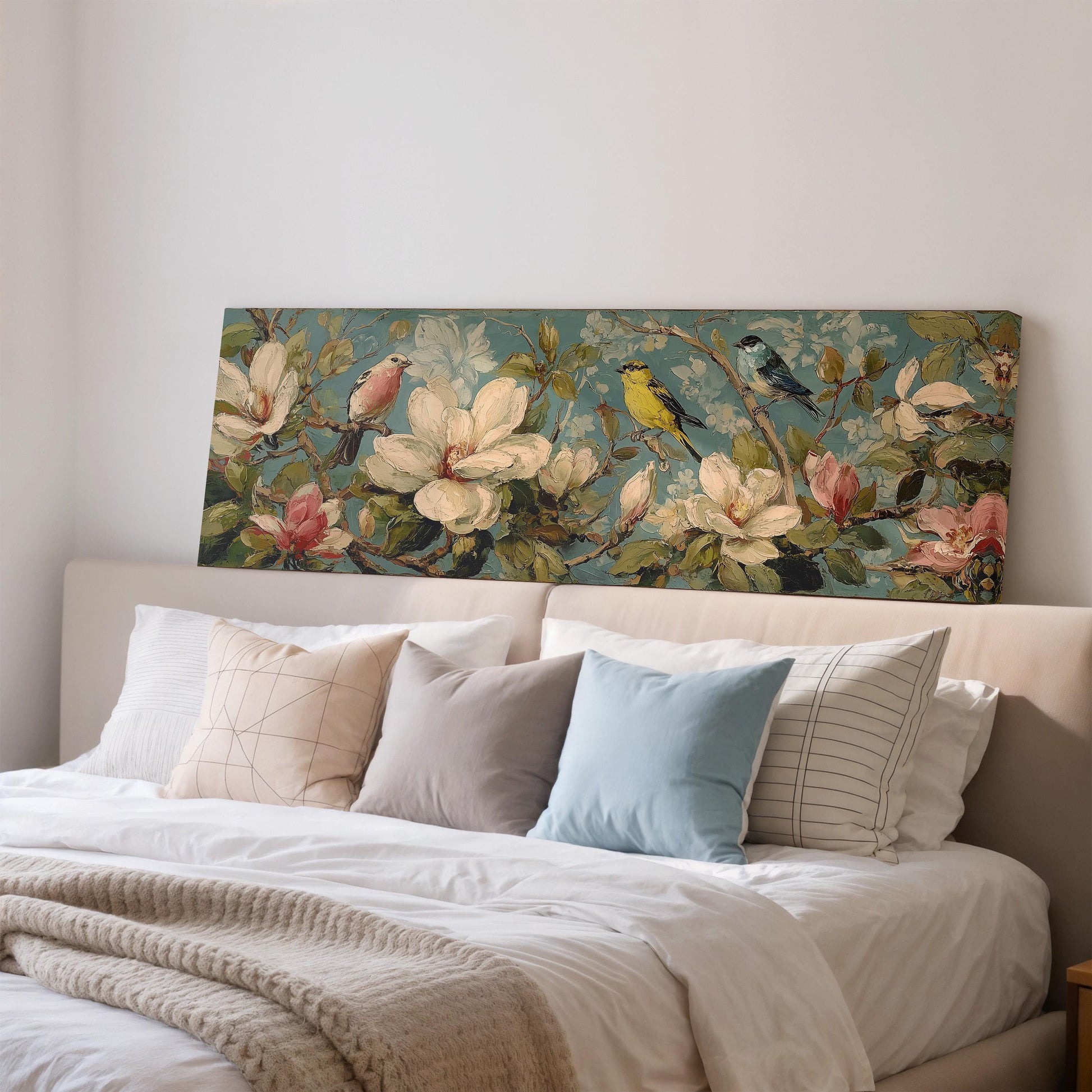 a large floral painting hanging on a wall above a bed with white pillows and a gray blanket.