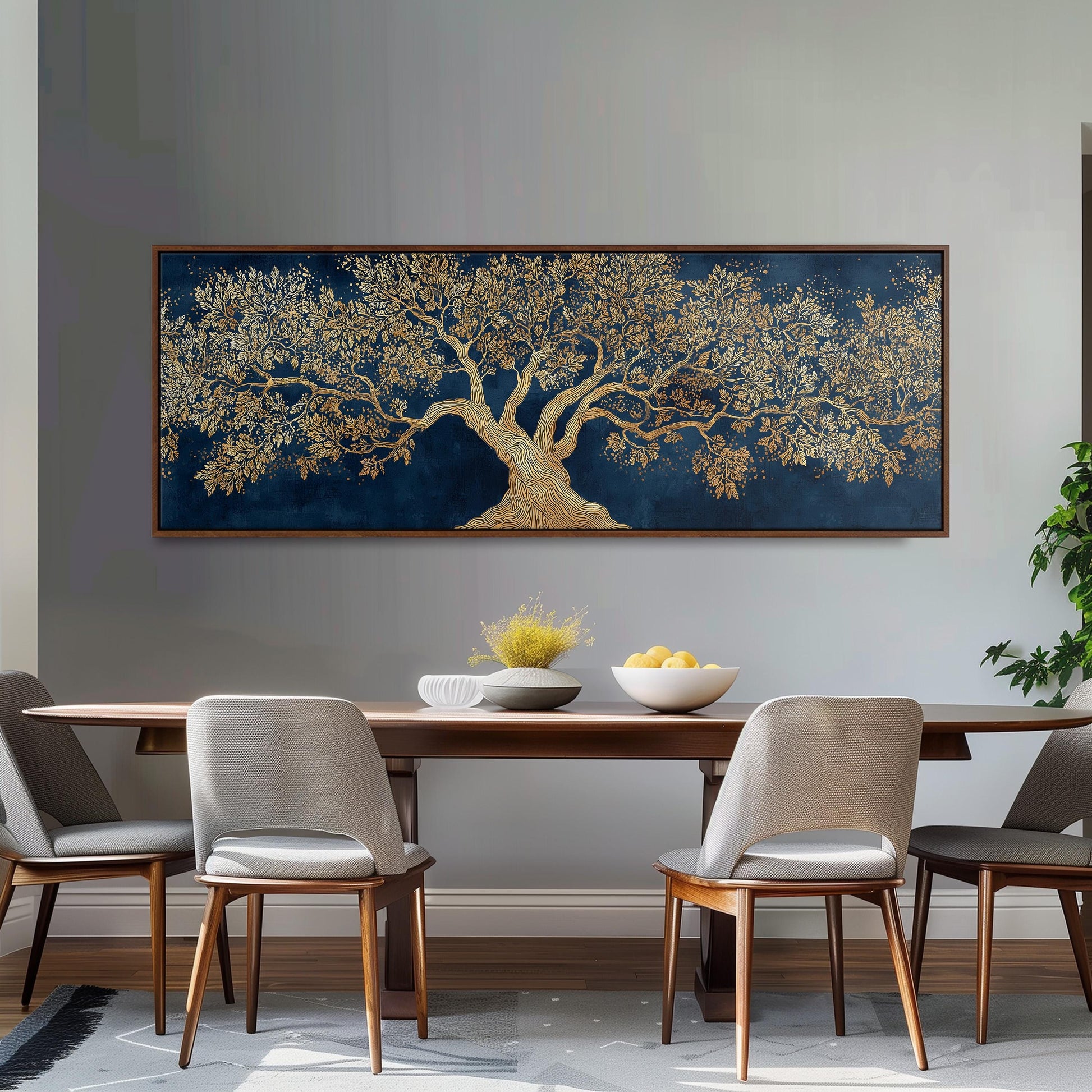 a dining room with a large, ornate tree painting hanging on the wall above a wooden dining table. The table is set with a bowl of fruit and a vase of flowers, creating a warm and inviting atmosphere. The room is furnished with four chairs, two on each side of the table, and a potted plant is visible on the right side of the room.