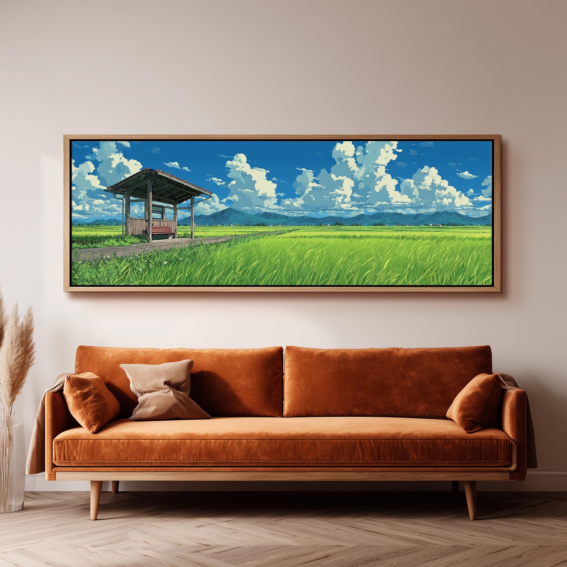 a large, framed painting of a serene landscape with a grassy field, a wooden structure, and a blue sky with white clouds. The painting is hung on a wall above a brown sofa with a wooden frame.