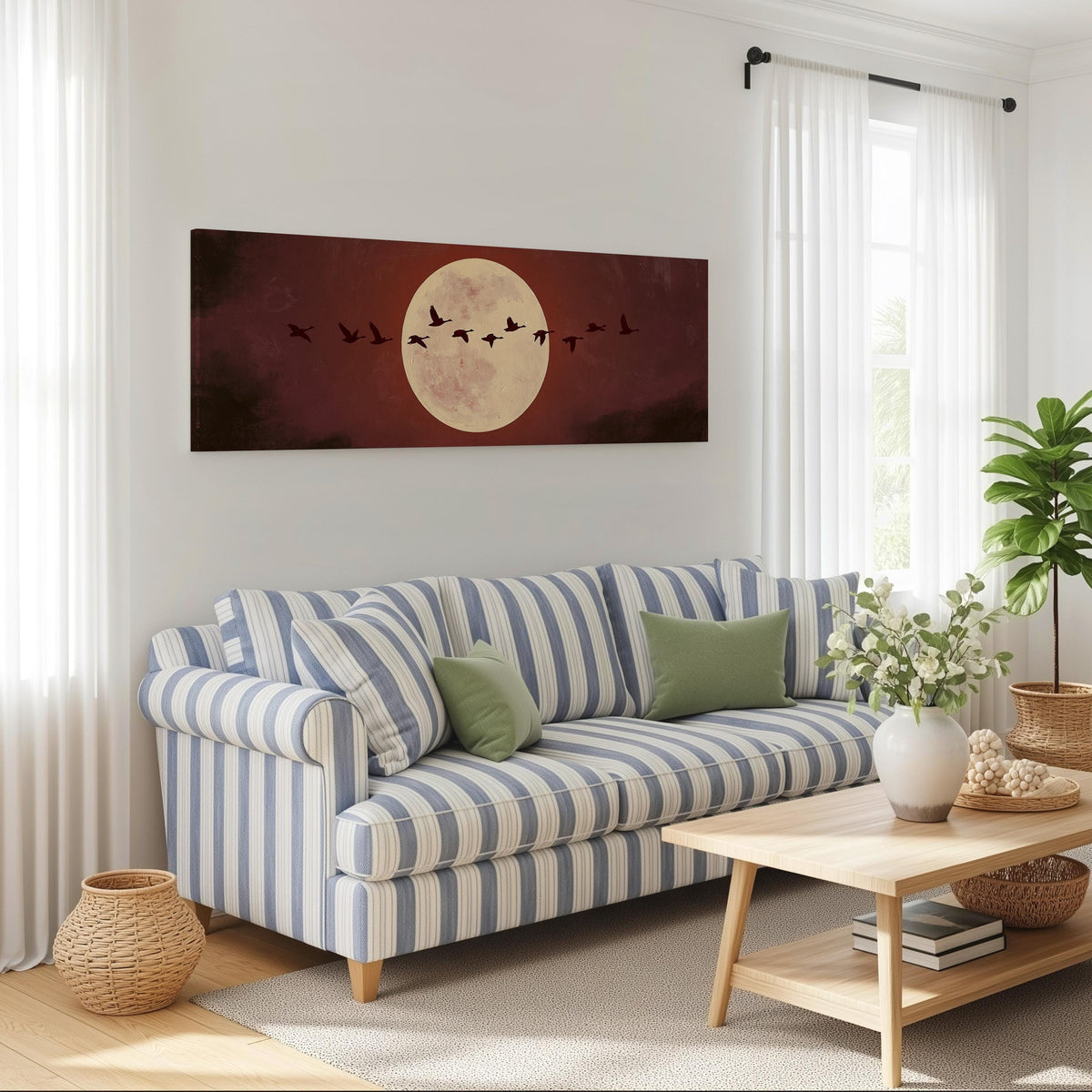 Geese crossing a pale moon on maroon long horizontal canvas print above a striped sofa in a coastal living room