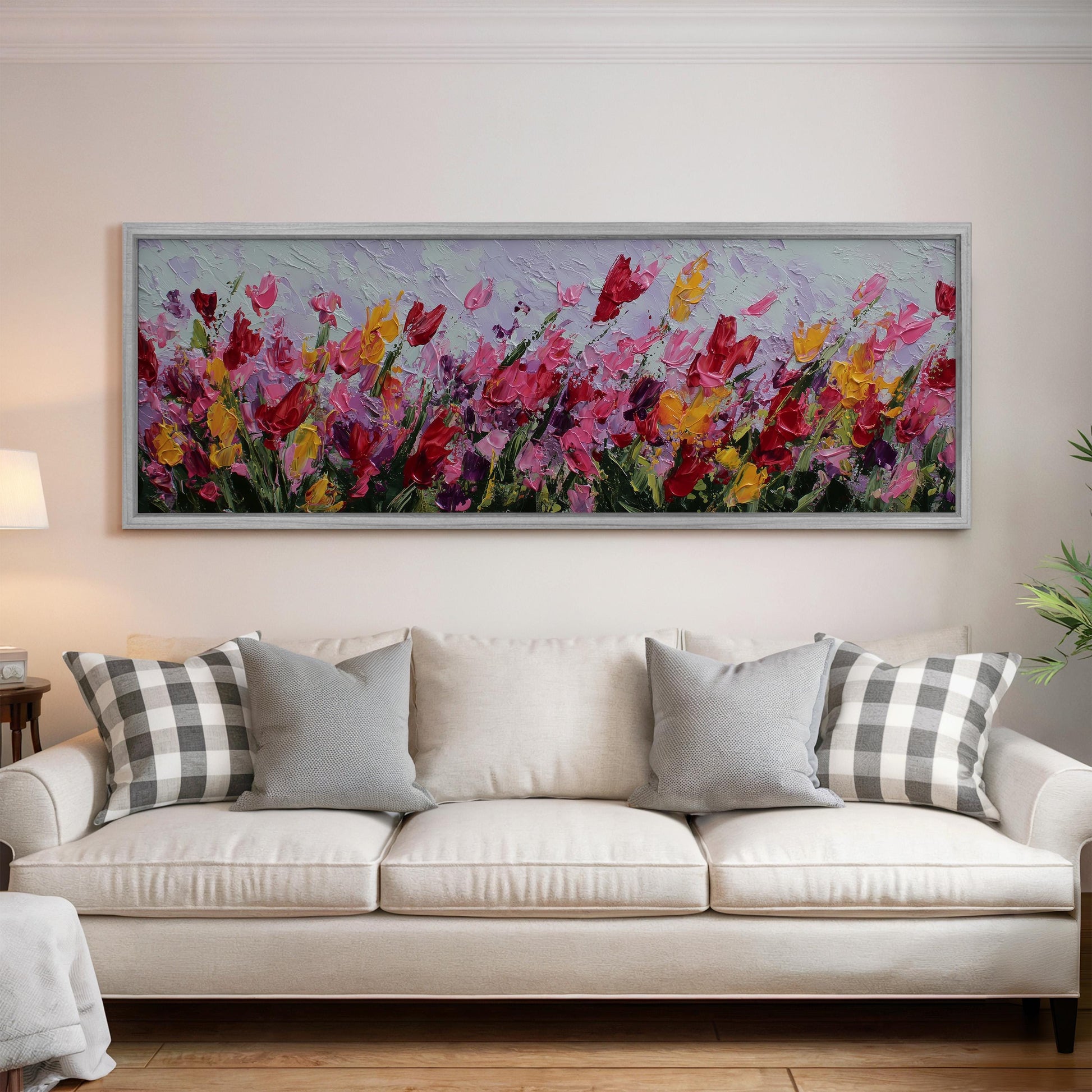 a large, colorful painting of flowers hanging on a wall above a white couch with gray and white pillows.