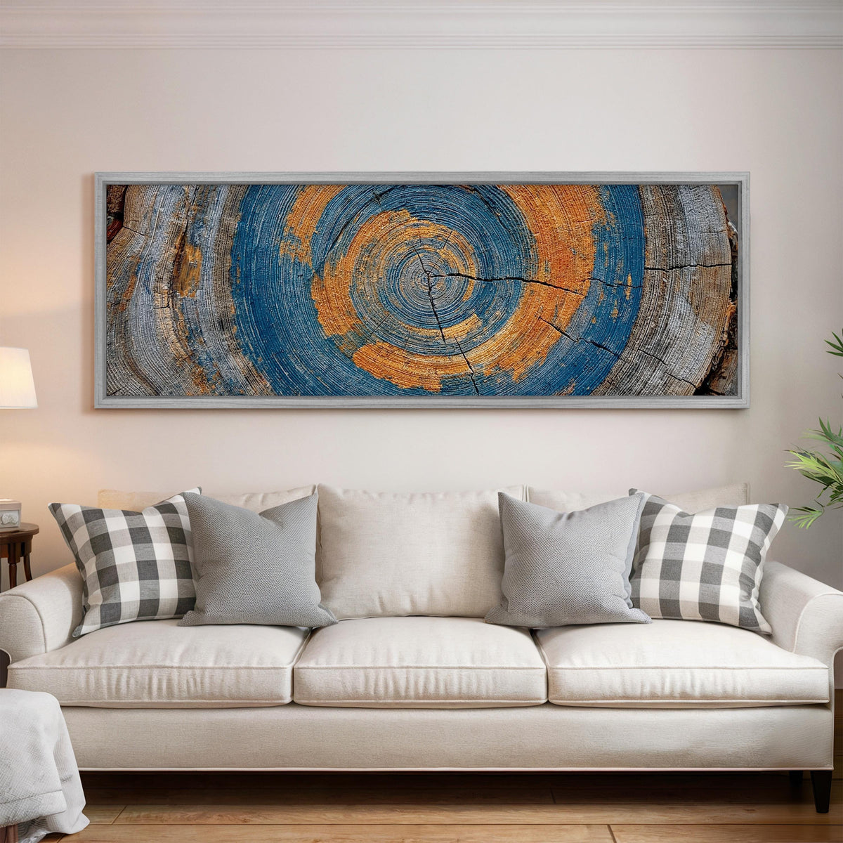 Blue and orange tree ring panoramic canvas print above a white sofa in a bright living room