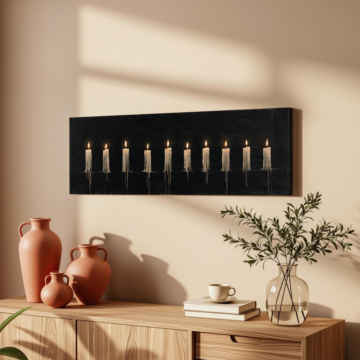 Ten lit candles on black long horizontal canvas print above a wooden sideboard