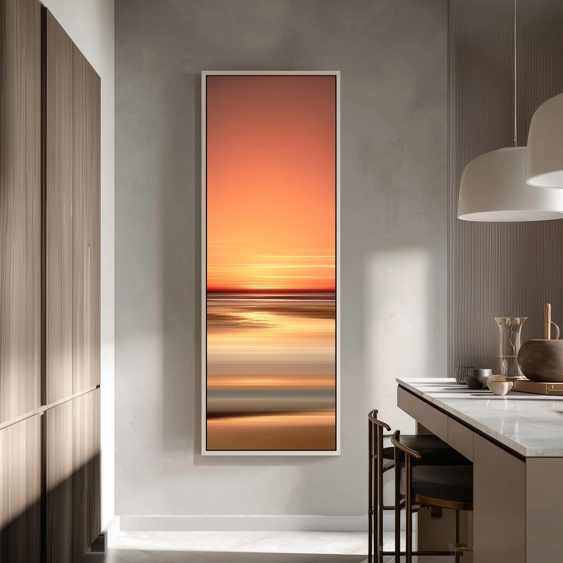 a modern kitchen with a large, vibrant painting of a sunset on the wall. The painting is framed in a white frame and hangs above a countertop with a sink and a chair. The kitchen has a minimalist design with a white countertop and a wooden cabinet.