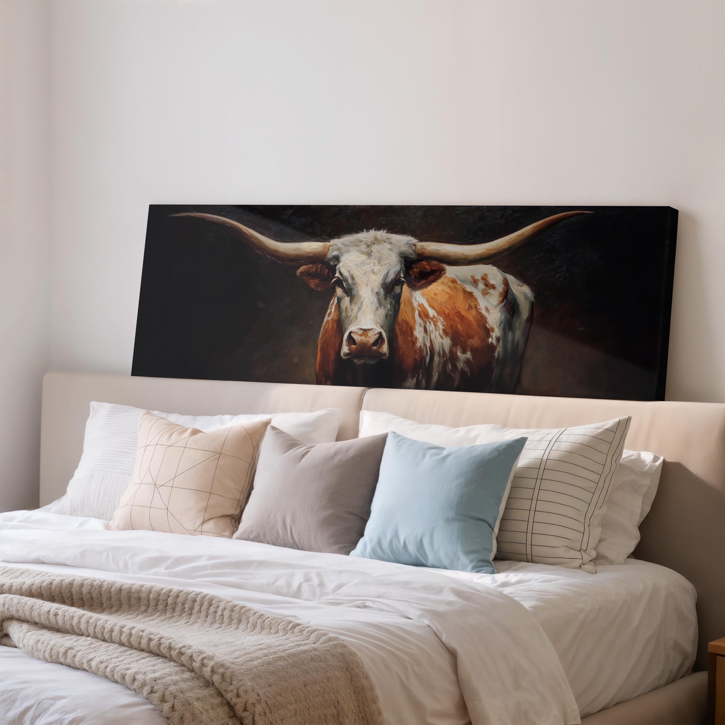 a large painting of a bull with long horns hanging above a bed with white sheets and pillows.