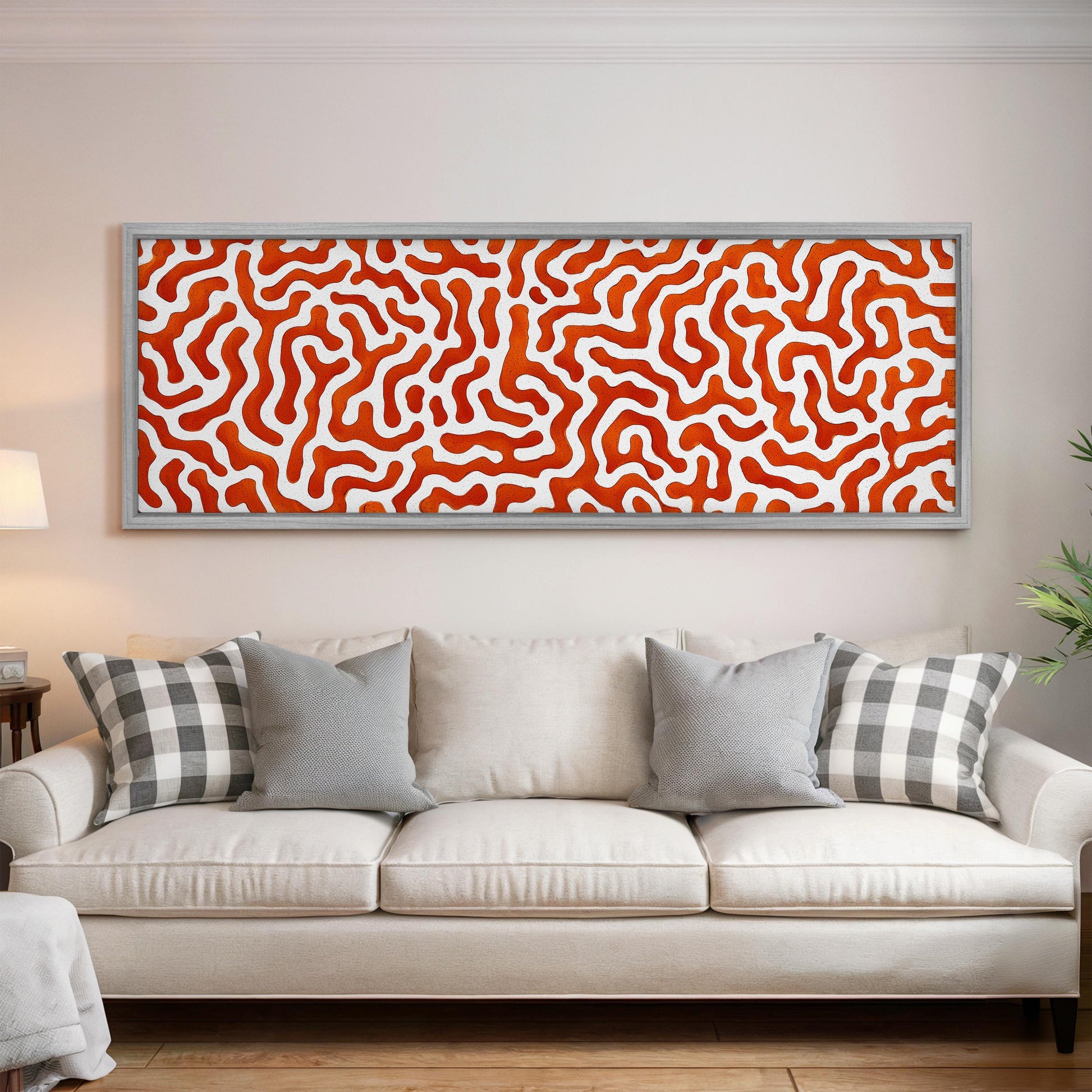 a large, white couch with gray and black plaid throw pillows, and a framed abstract painting hanging above it on the wall.