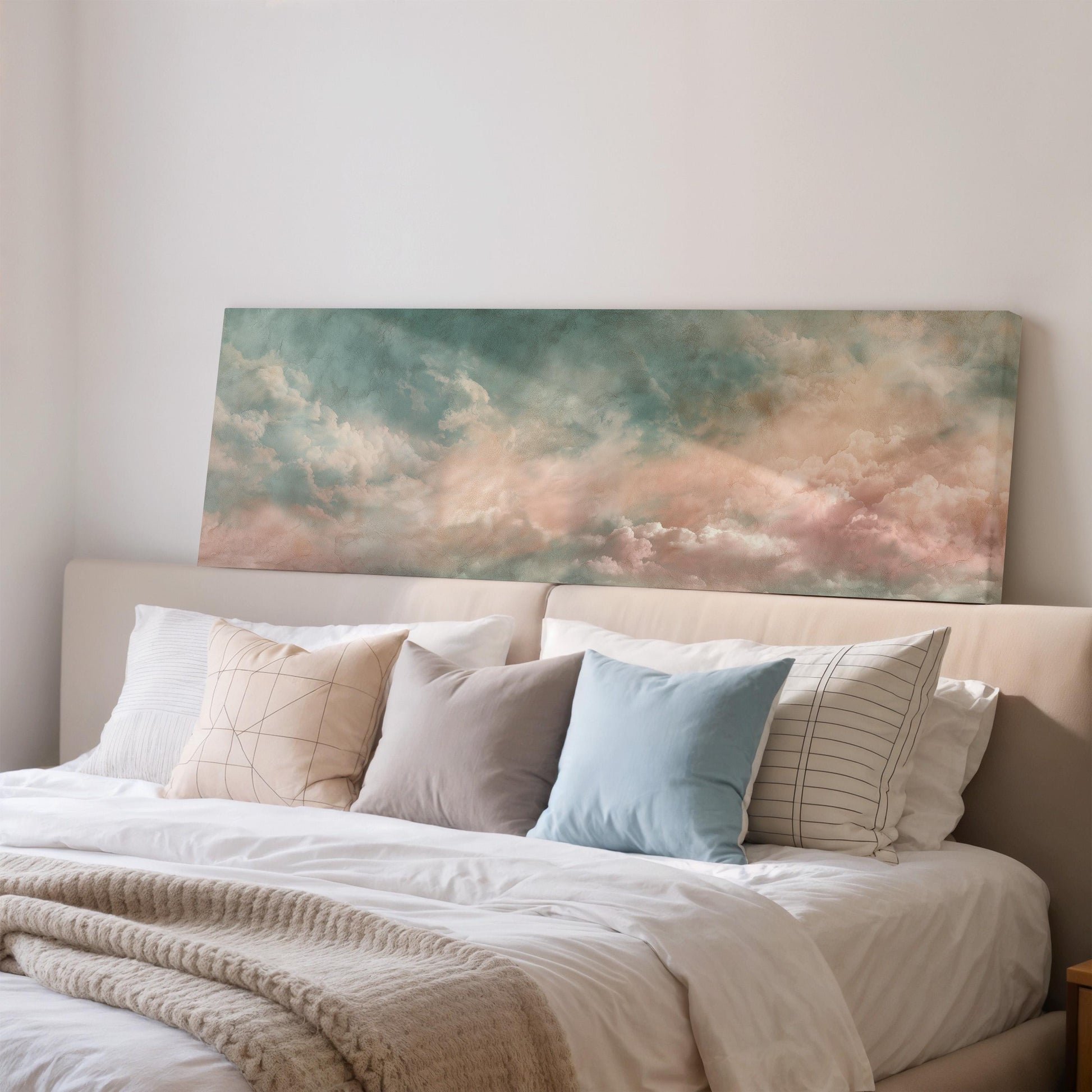 a cozy bedroom with a large bed adorned with white sheets and a blue pillow. Above the bed, there is a large canvas print depicting a serene landscape with a cloudy sky.
