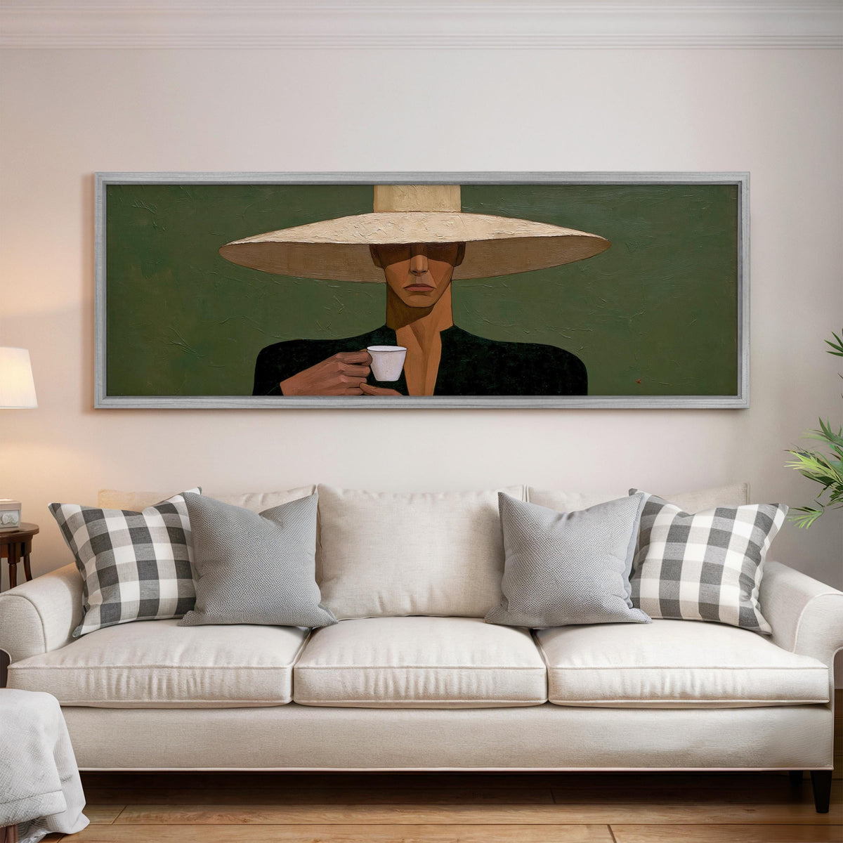 Shadowed woman in a sun hat with espresso panoramic canvas print above a white sofa in a bright living room