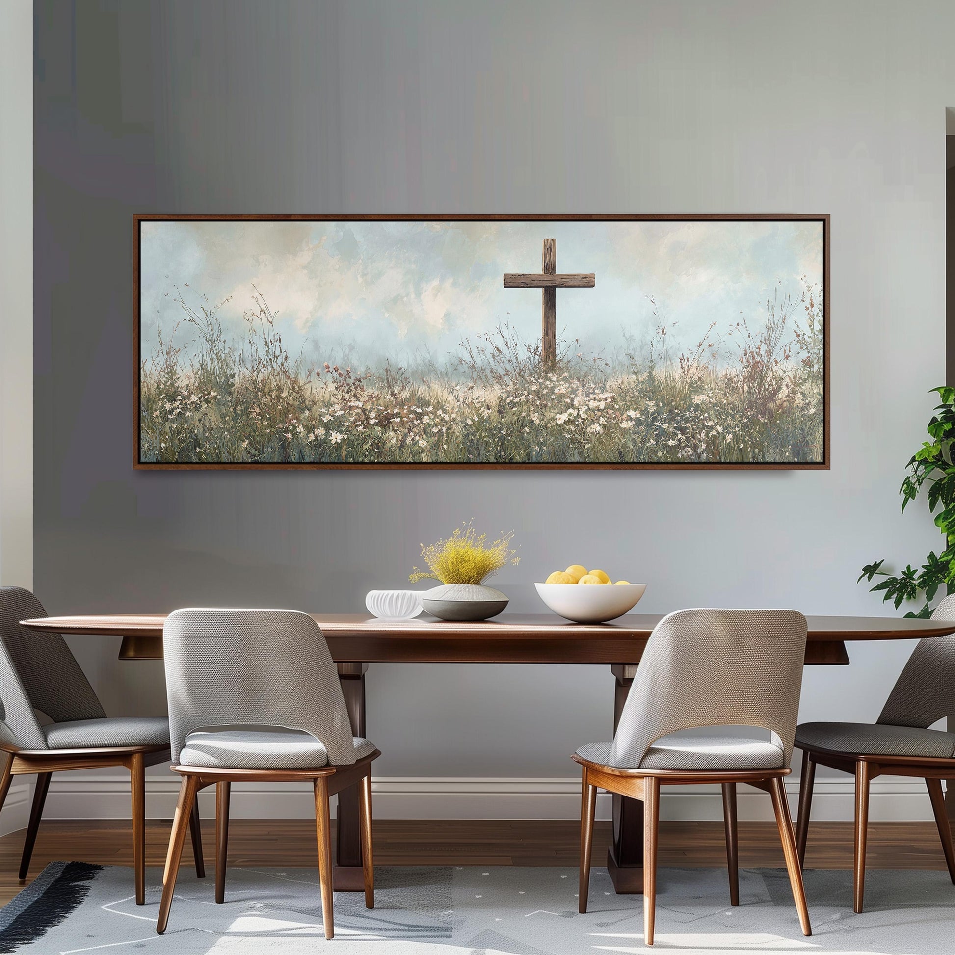 a dining room with a large painting of a cross in a field above a wooden table with four chairs. The painting is framed and hangs on the wall above the table.