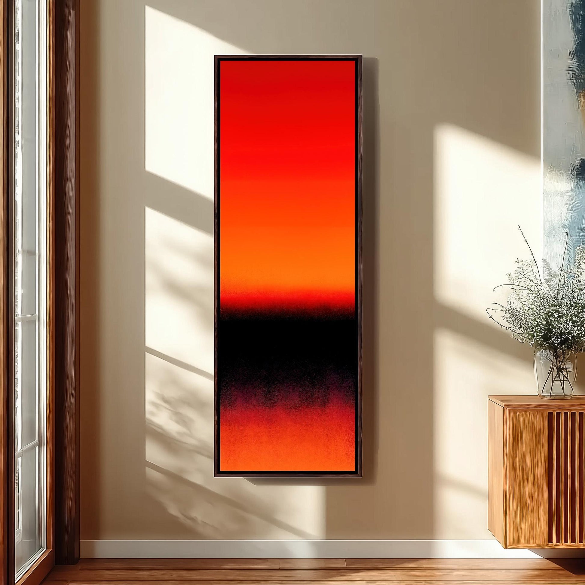 a large, rectangular painting with a gradient of red and black colors, hanging on a wall in a room with a wooden cabinet and a vase of flowers.