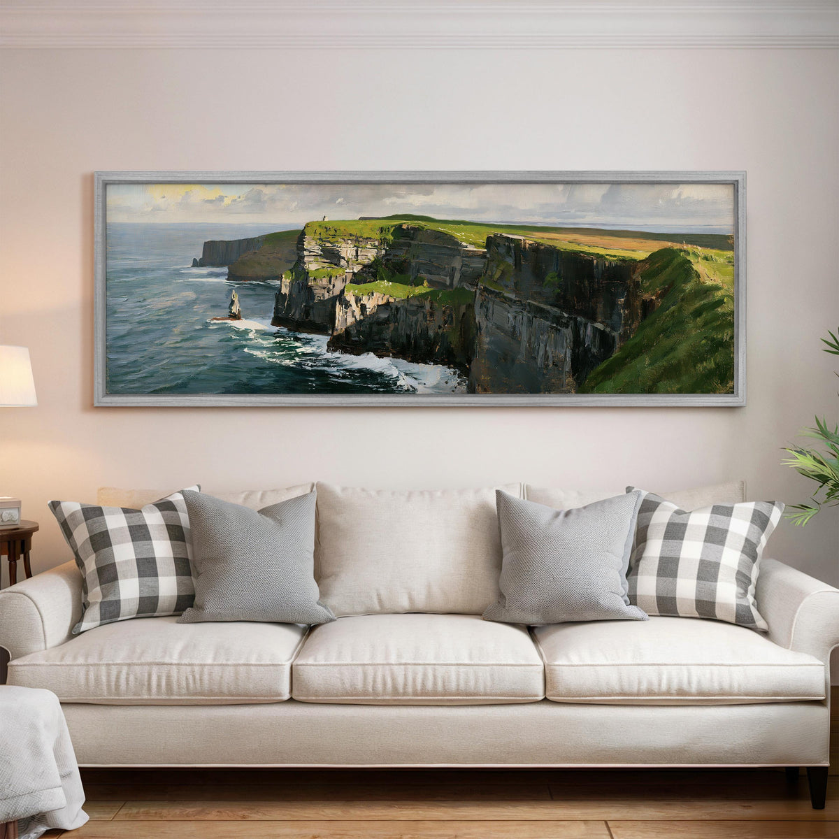 Sunlit sea cliffs with a sea stack panoramic canvas print above a white sofa in a bright living room