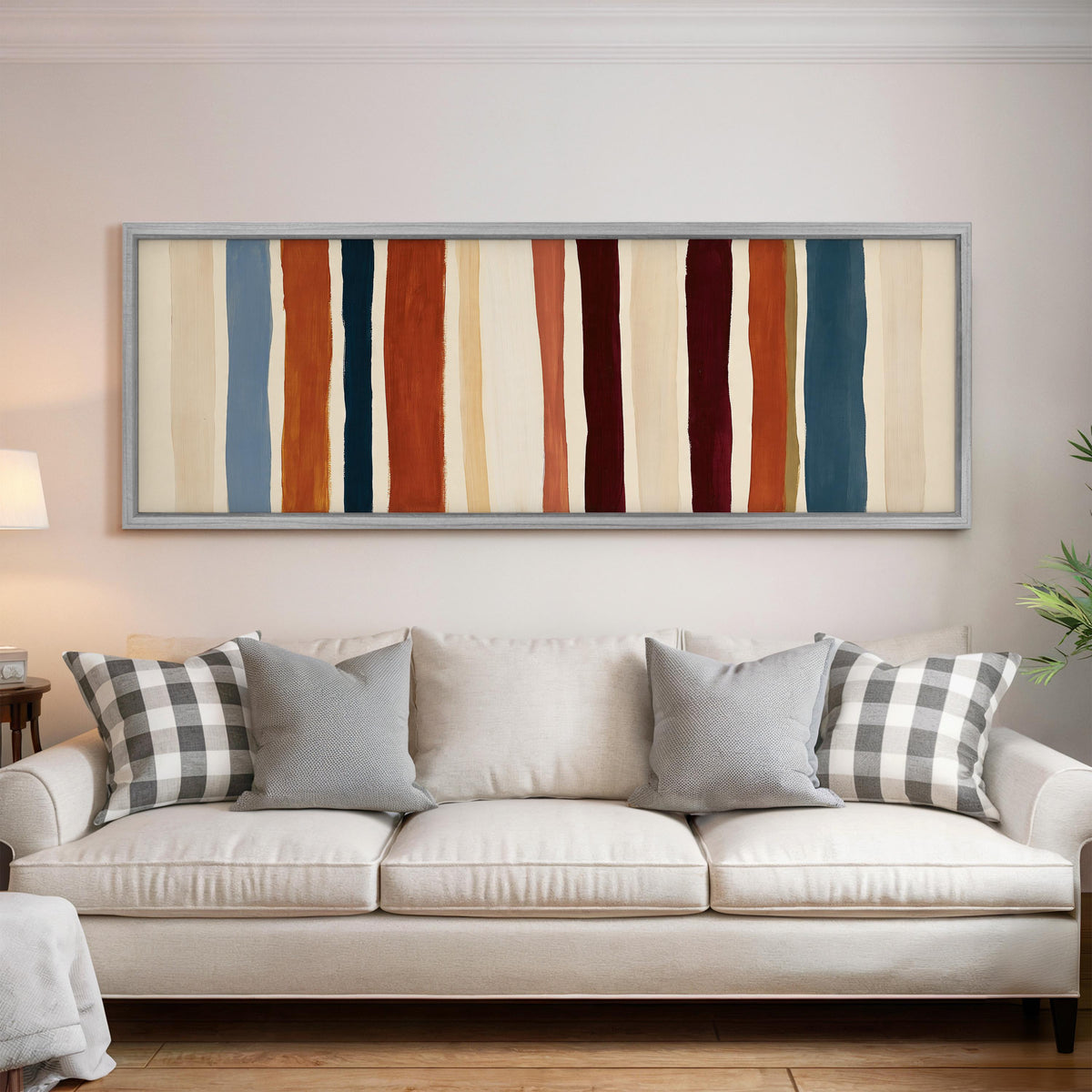 Rust, navy and maroon stripes panoramic canvas print above a white sofa in a bright living room