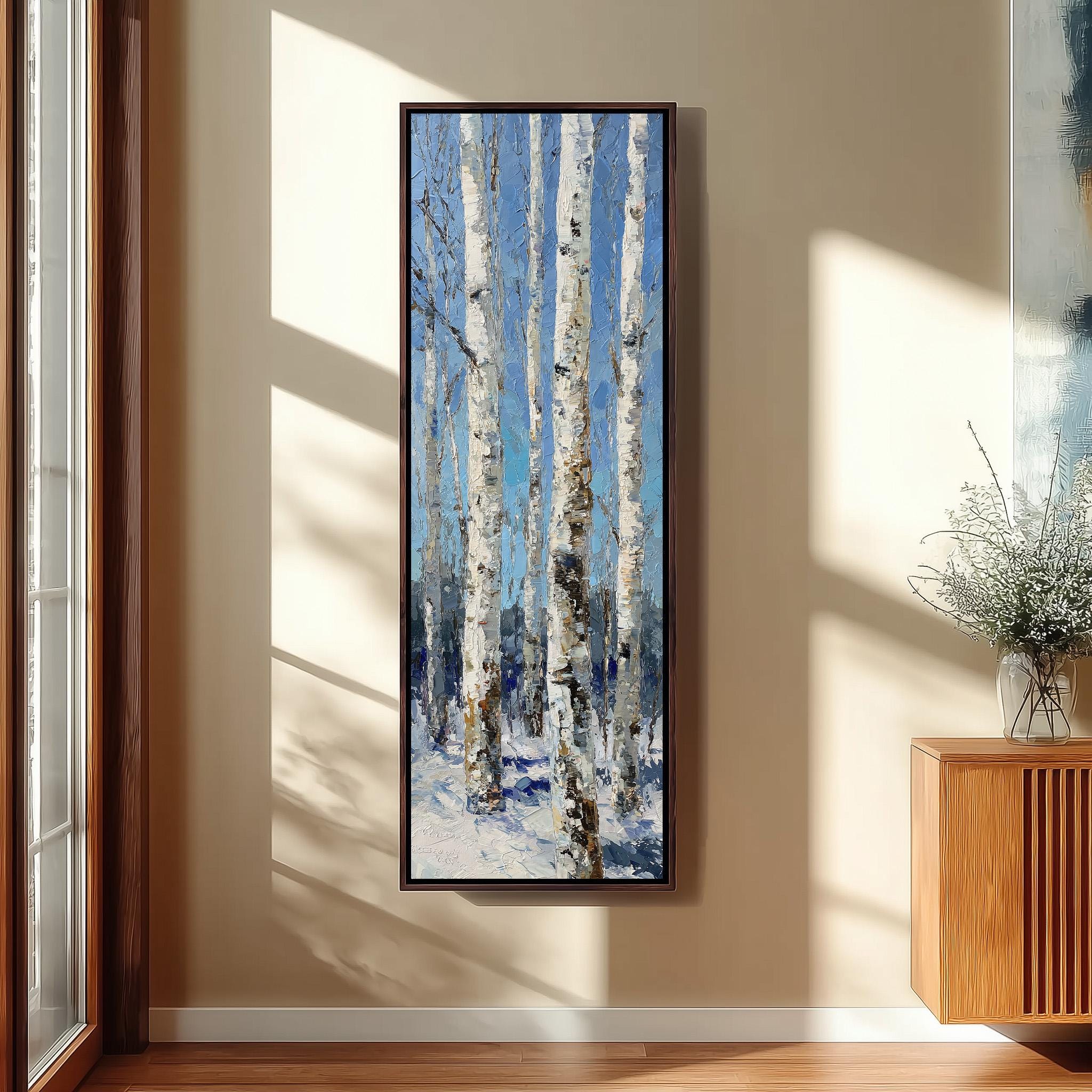 a large painting of a snowy forest with tall trees, hanging on a wall in a room with a wooden cabinet and a vase of flowers.