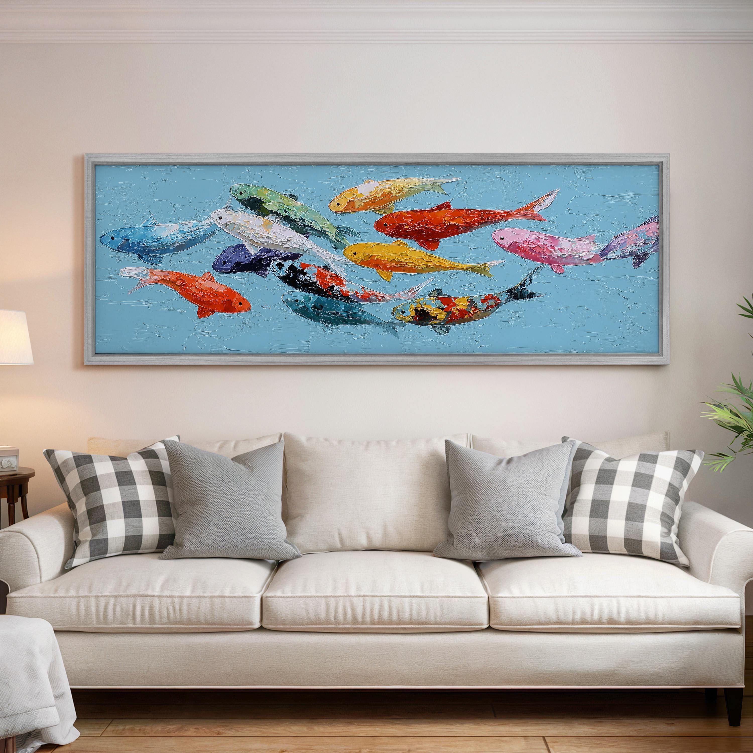 a large, colorful painting of fish on a blue background, hanging on a wall above a white couch with gray and white patterned pillows.