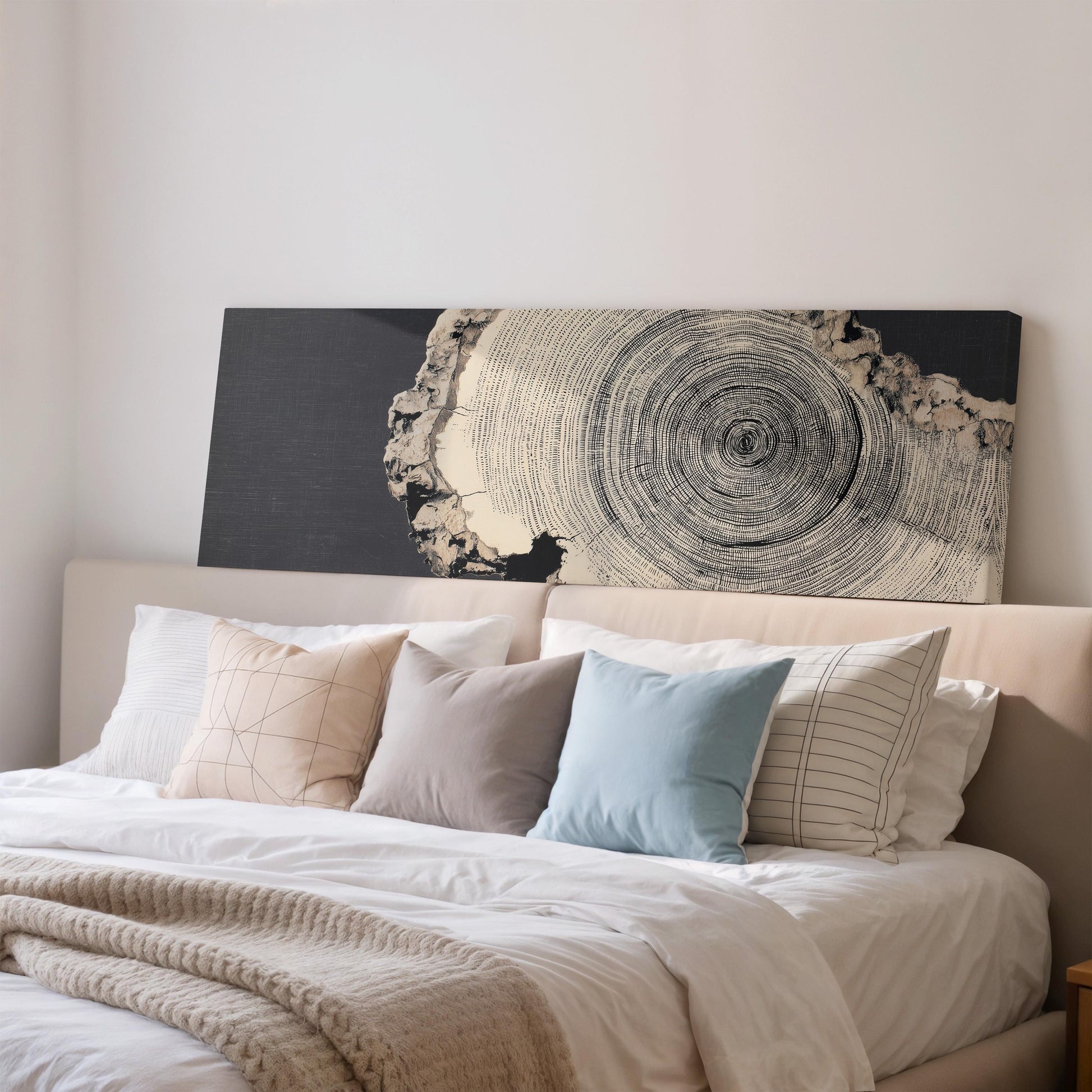 a well-made bed with a black and white tree trunk artwork on the headboard, creating a unique and stylish bedroom decor.