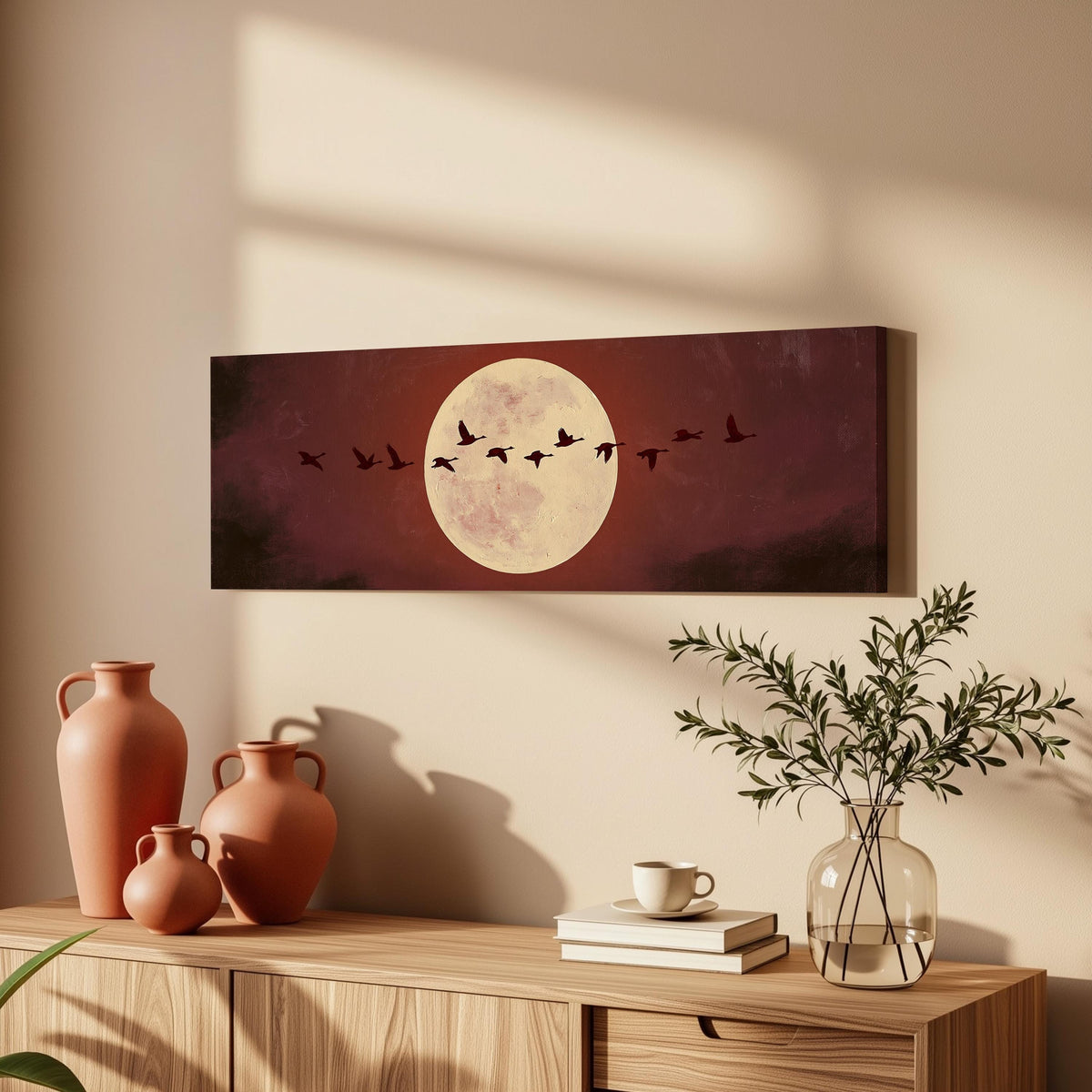 Geese crossing a pale moon on maroon long horizontal canvas print above a wooden sideboard