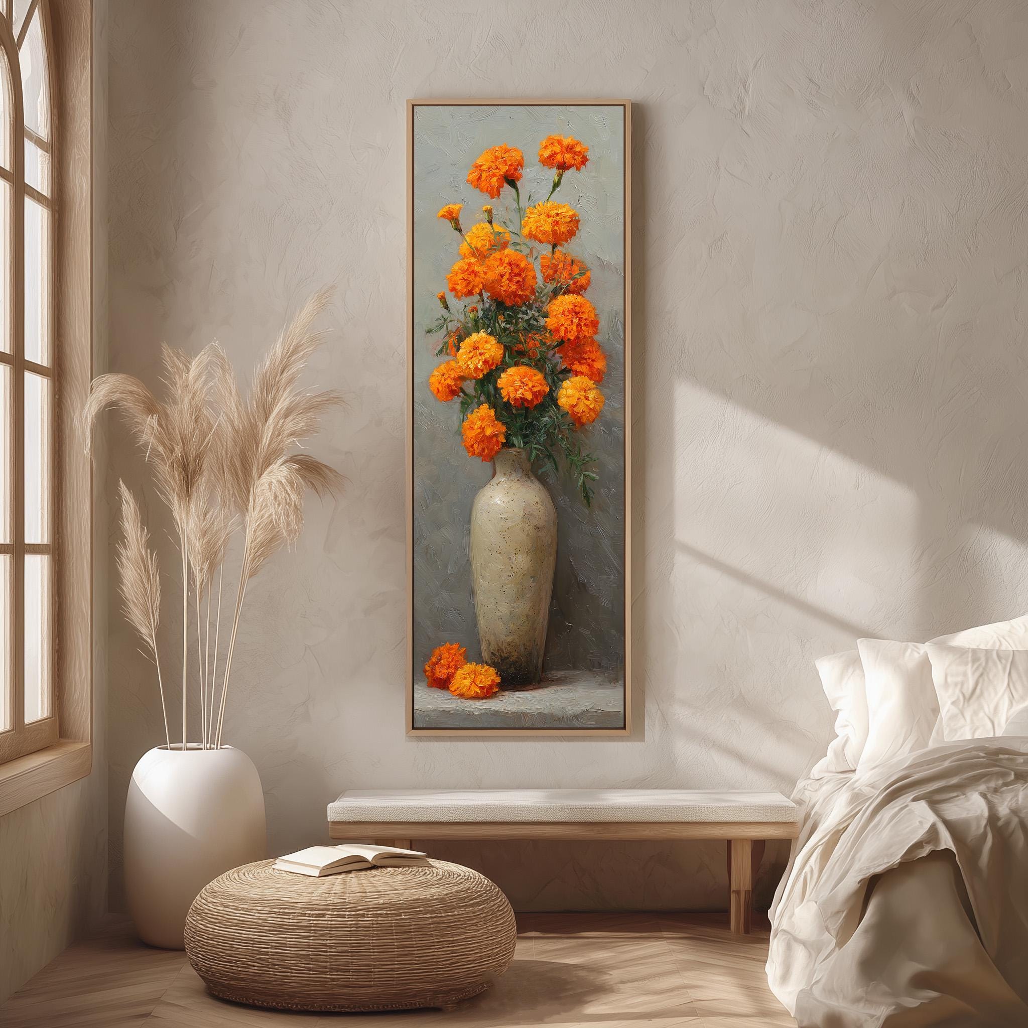 a large painting of a vase filled with orange flowers hanging on a wall in a room with a bed, a potted plant, and a woven ottoman.