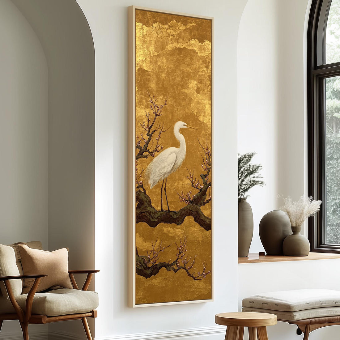 a large framed painting of a white crane standing on a branch with flowers, hanging on a wall in a room with a wooden cabinet and a vase of flowers.