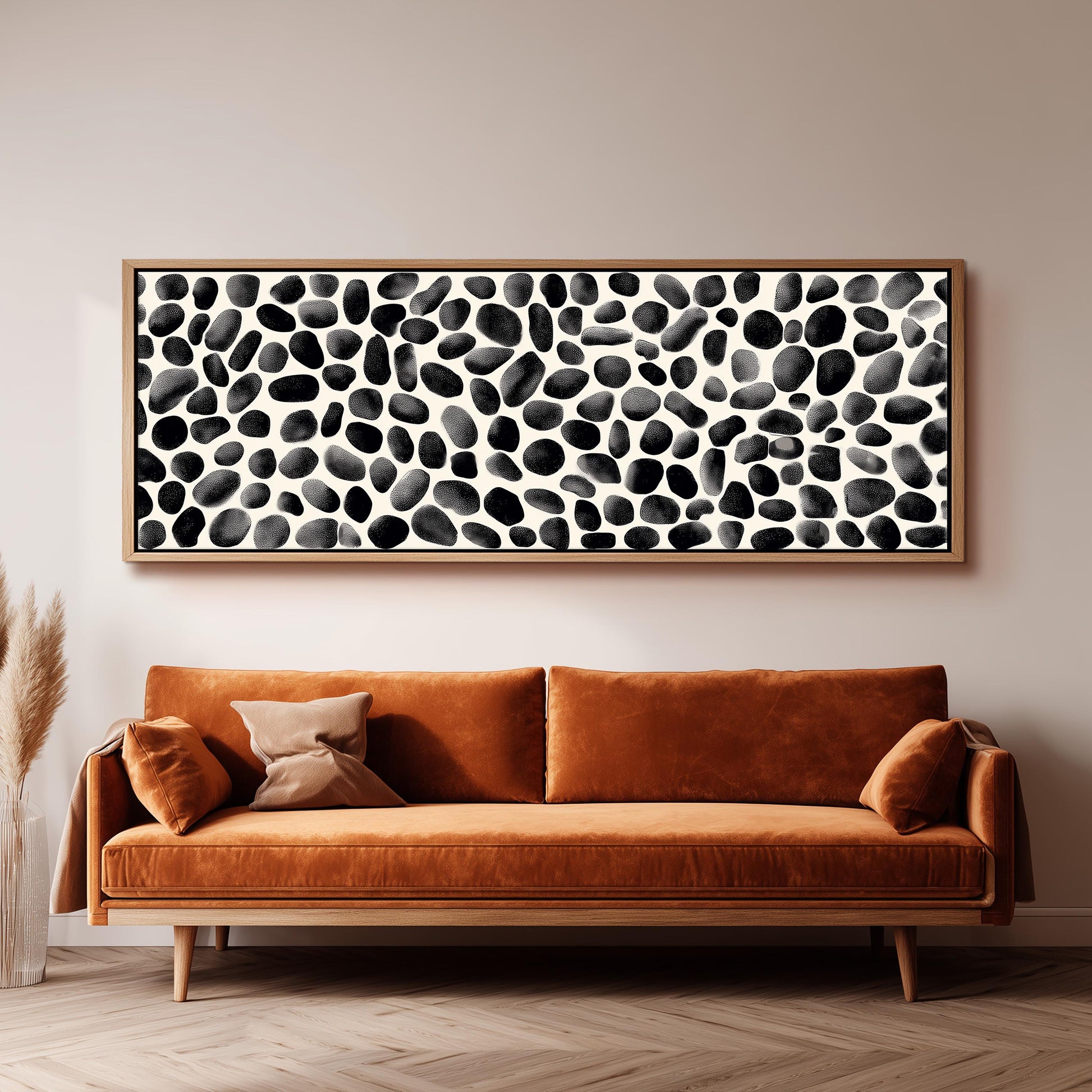 a large black and white abstract painting hanging on a wall above a brown sofa with two pillows.