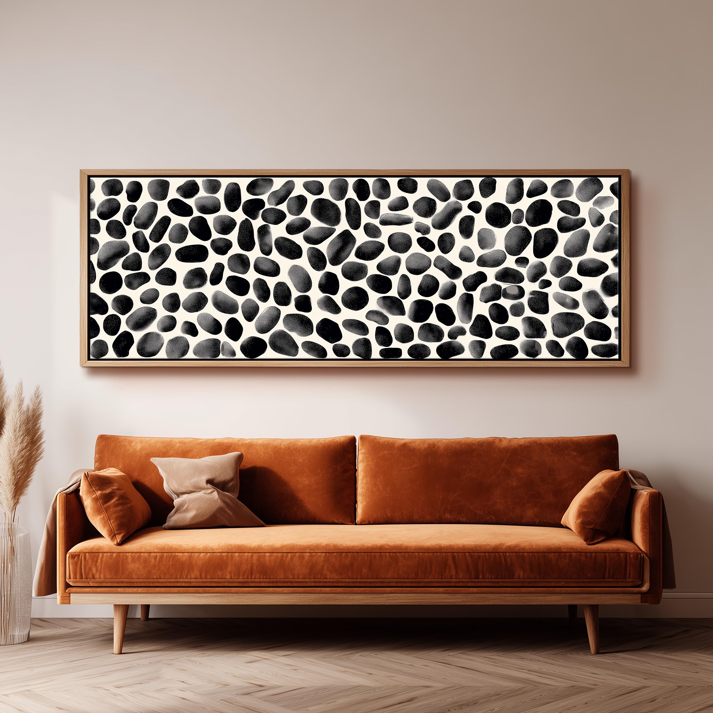 a large black and white abstract painting hanging on a wall above a brown sofa with two pillows.
