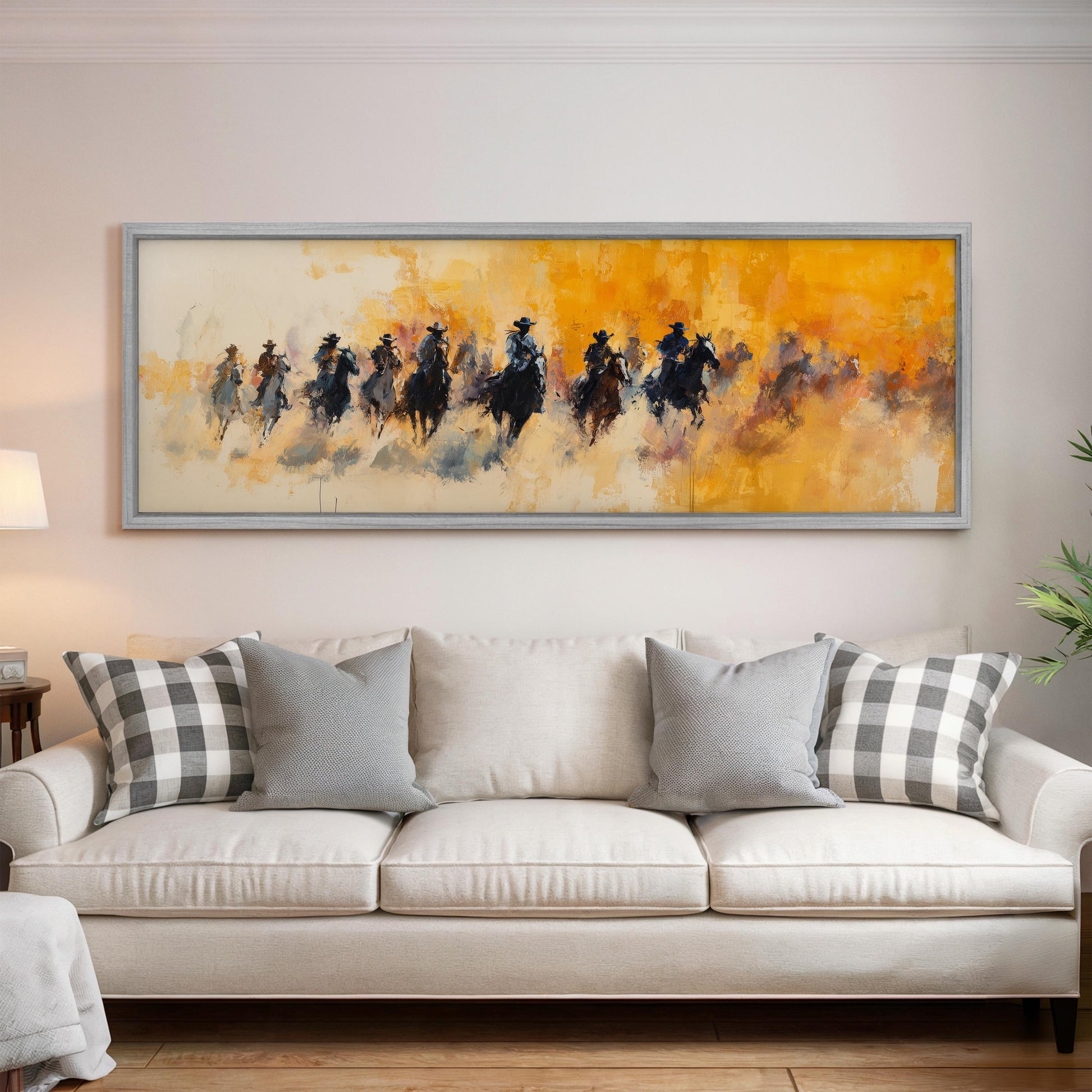 a large painting of a group of people riding horses, hanging on a wall above a white couch with gray and white plaid throw pillows.