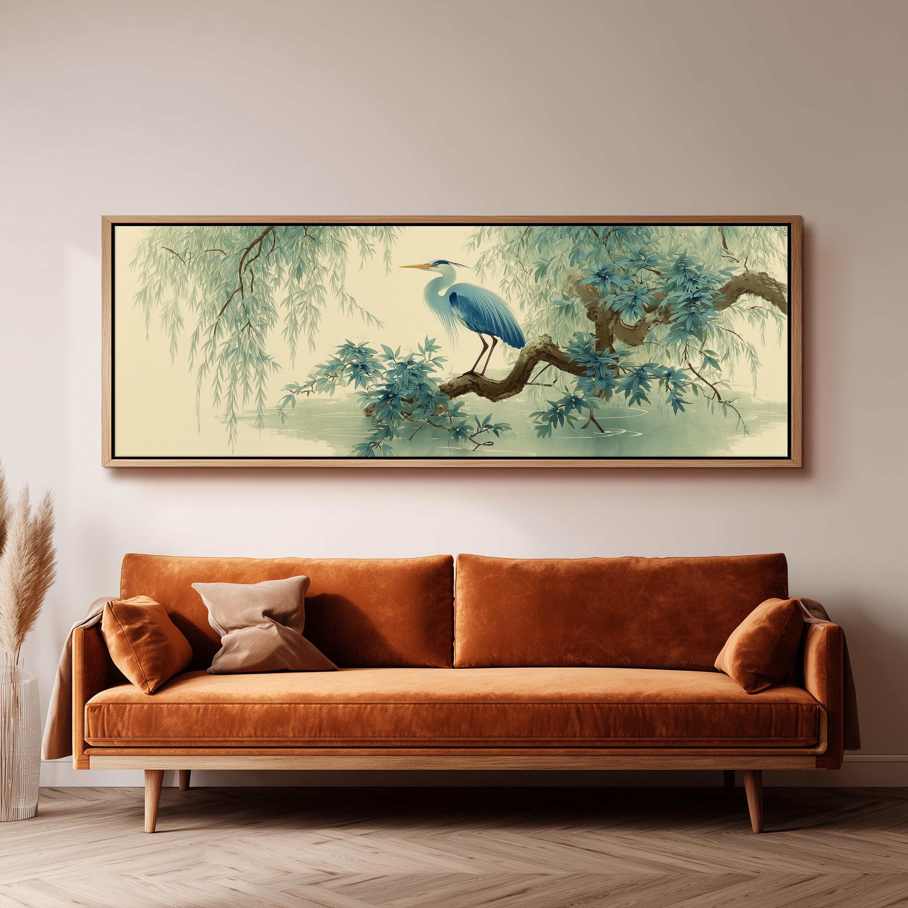 a large, framed painting of a blue heron perched on a branch, hanging on a wall above a brown sofa.