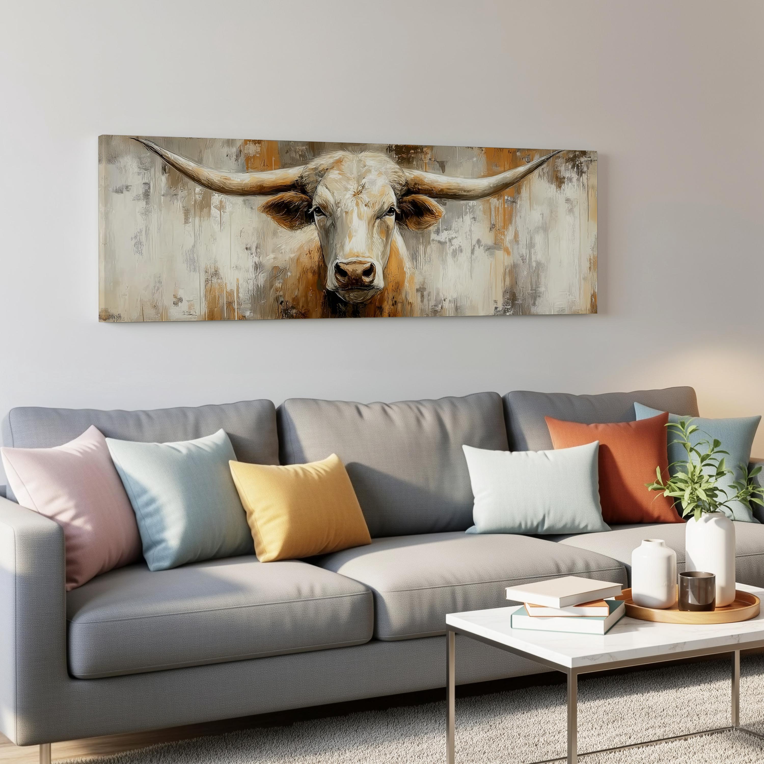 a large painting of a bull's head hanging on a wall above a gray couch with colorful throw pillows.