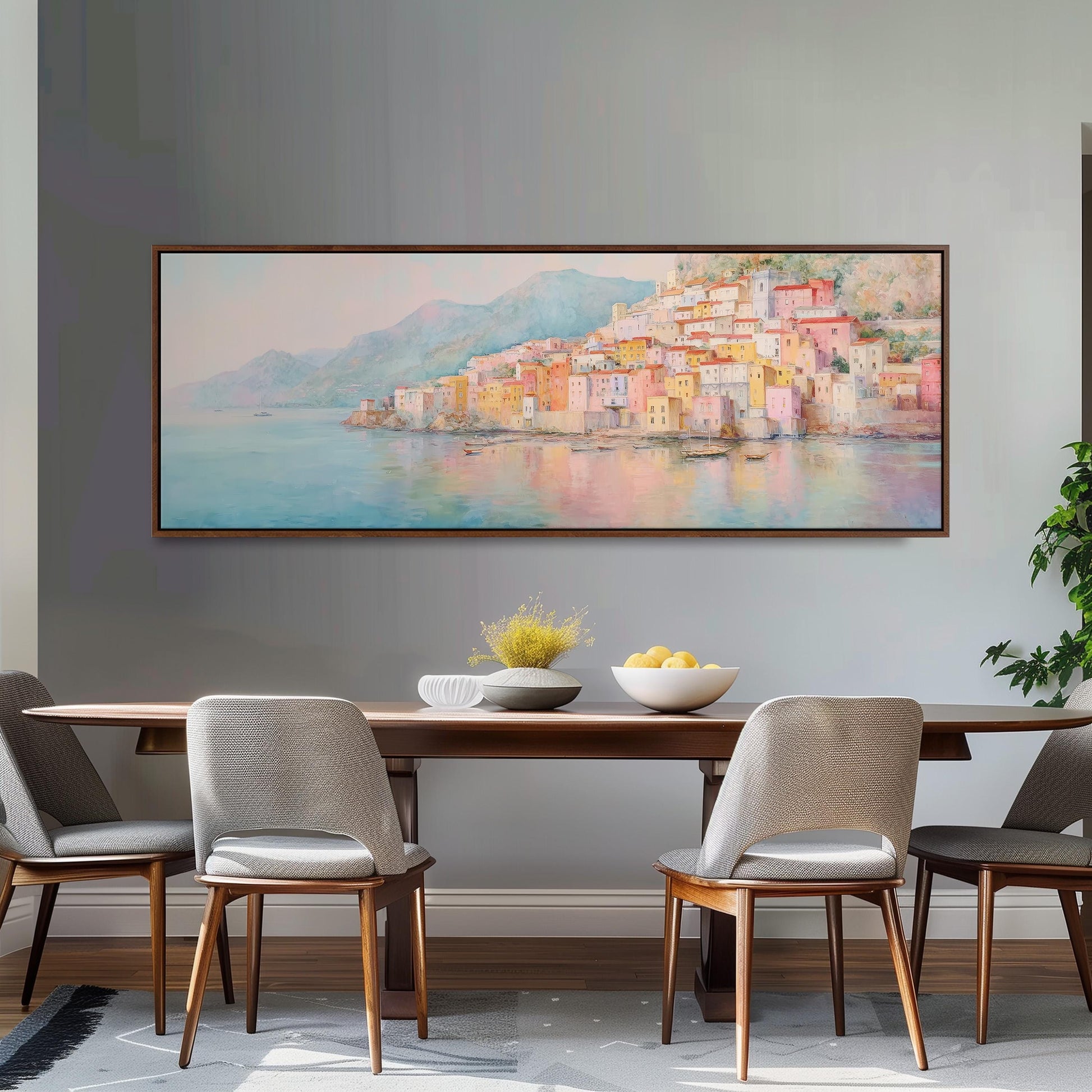 a dining room with a large painting of a coastal town hanging on the wall above a wooden dining table with four chairs. The painting depicts a picturesque seaside town with colorful buildings and a harbor in the background.