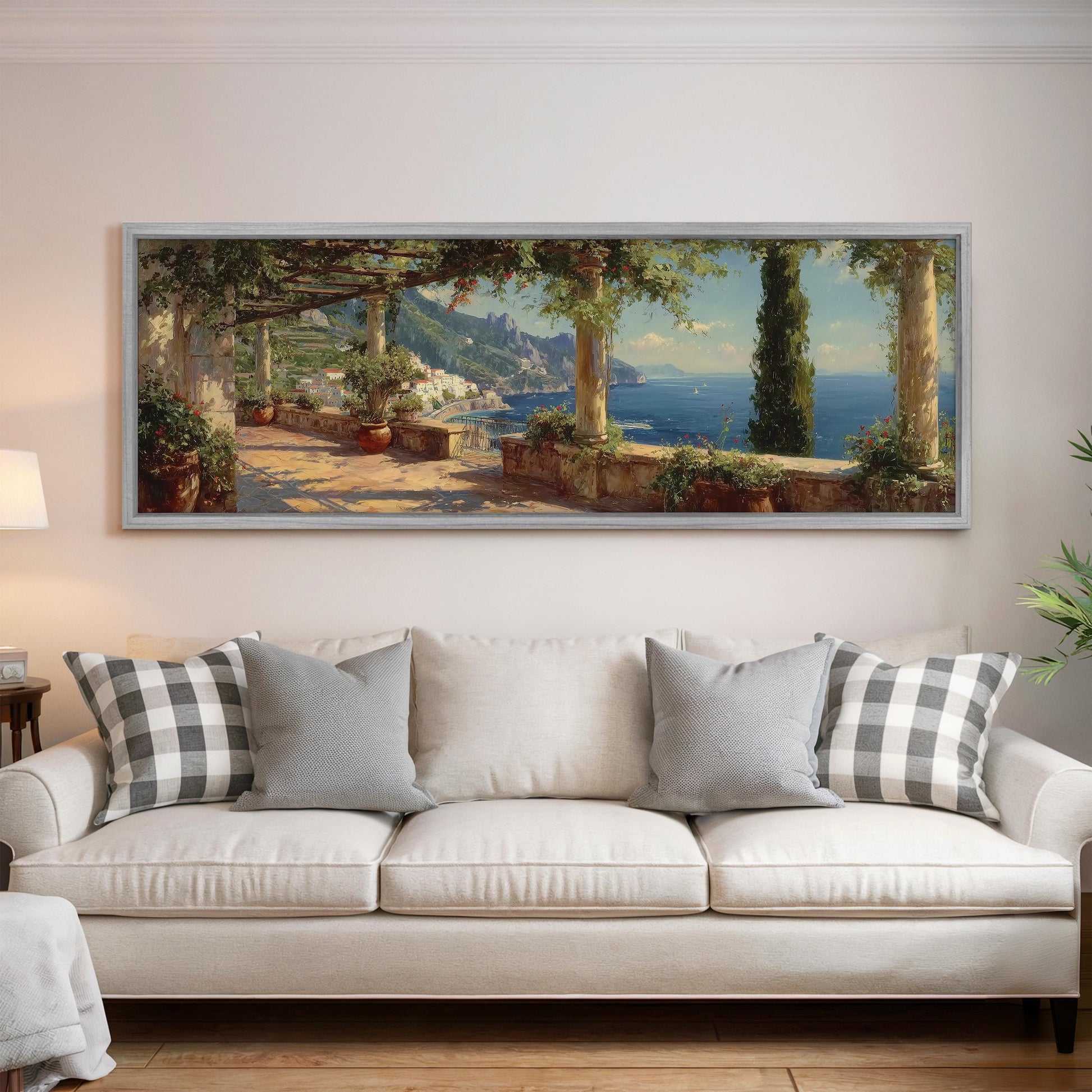 a large painting of a scenic coastal landscape hanging on a wall above a white sofa with decorative pillows.