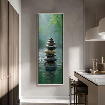 a large framed painting of a stack of stones in a tranquil, natural setting, with water below creating a reflective surface.