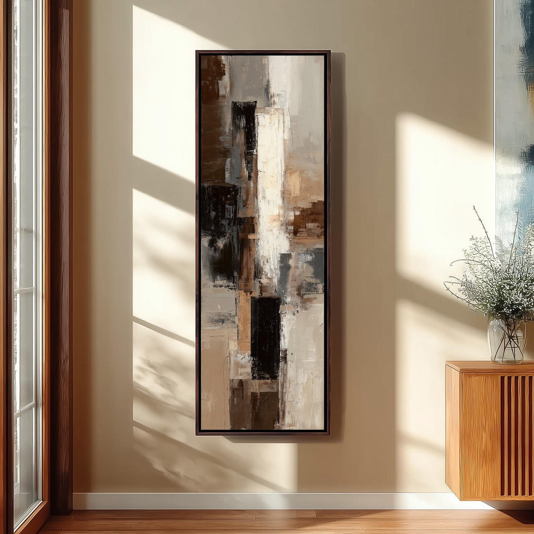 a modern kitchen with a large abstract painting hanging on the wall above a counter. The painting has a mix of brown, white, and black colors, creating a visually striking contrast. The kitchen is well-lit, with natural light coming in from a window on the left side of the image. The counter is equipped with a sink and a few decorative items, such as a vase and a bowl.