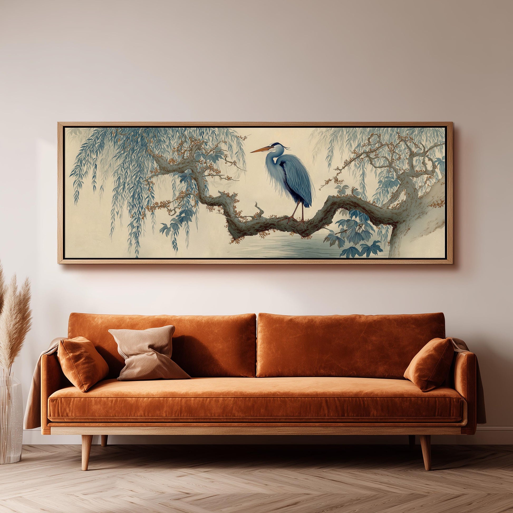 a large, framed painting of a blue heron perched on a branch, hanging on a wall above a brown sofa.