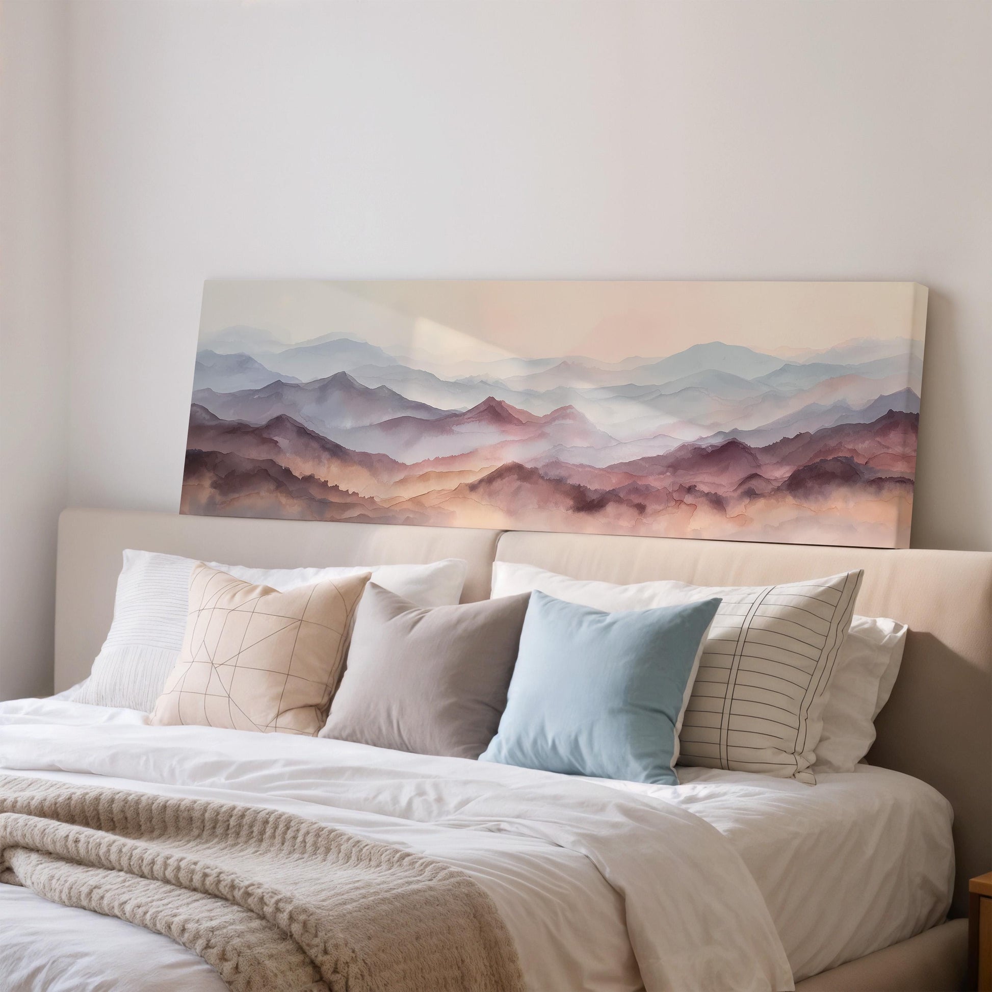 a large, framed painting of a mountain landscape hanging above a bed with white bedding and various pillows.