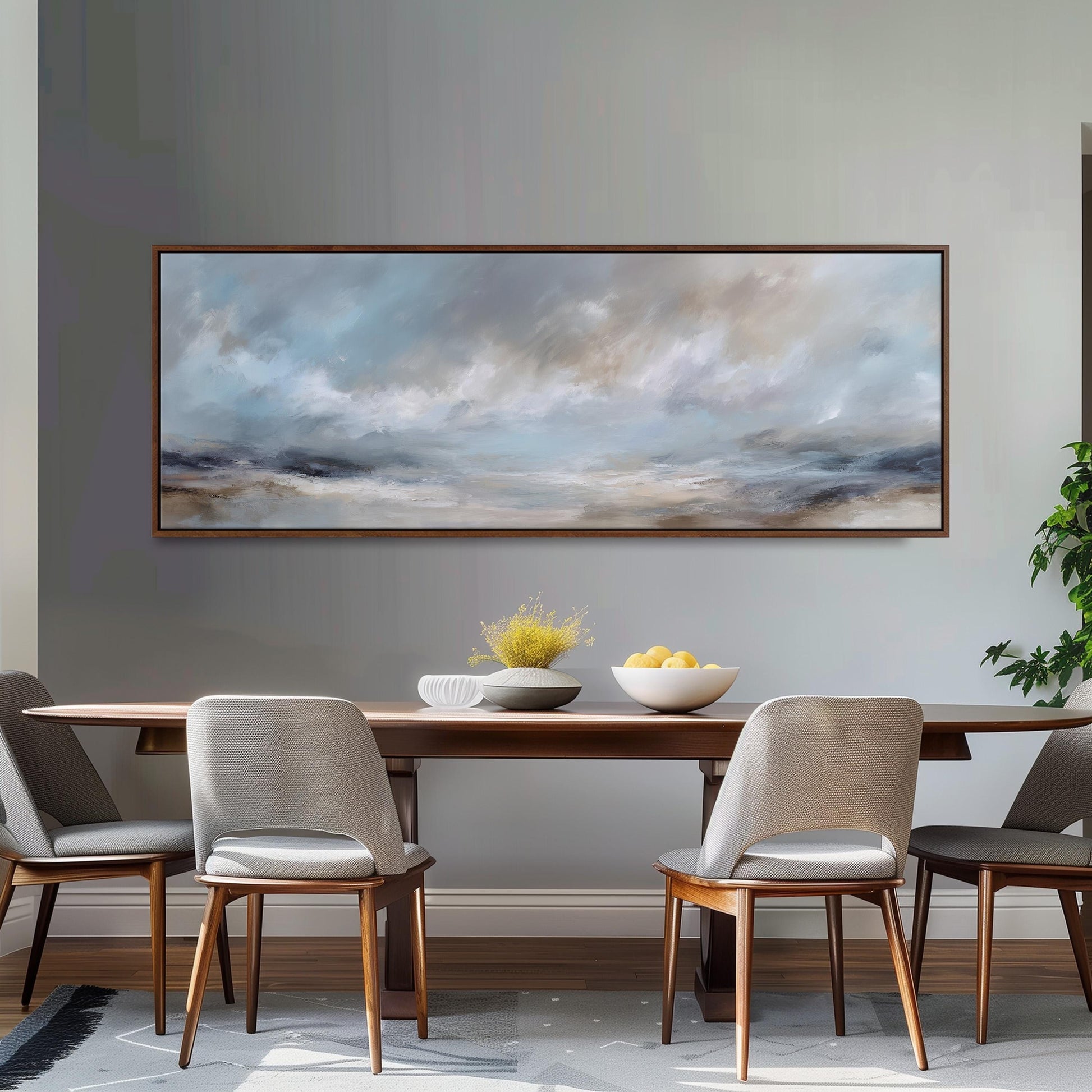 a dining room with a large painting of a cloudy sky hanging on the wall above a wooden dining table with four chairs. The table is set with a bowl of fruit and a vase of flowers, creating a cozy and inviting atmosphere.