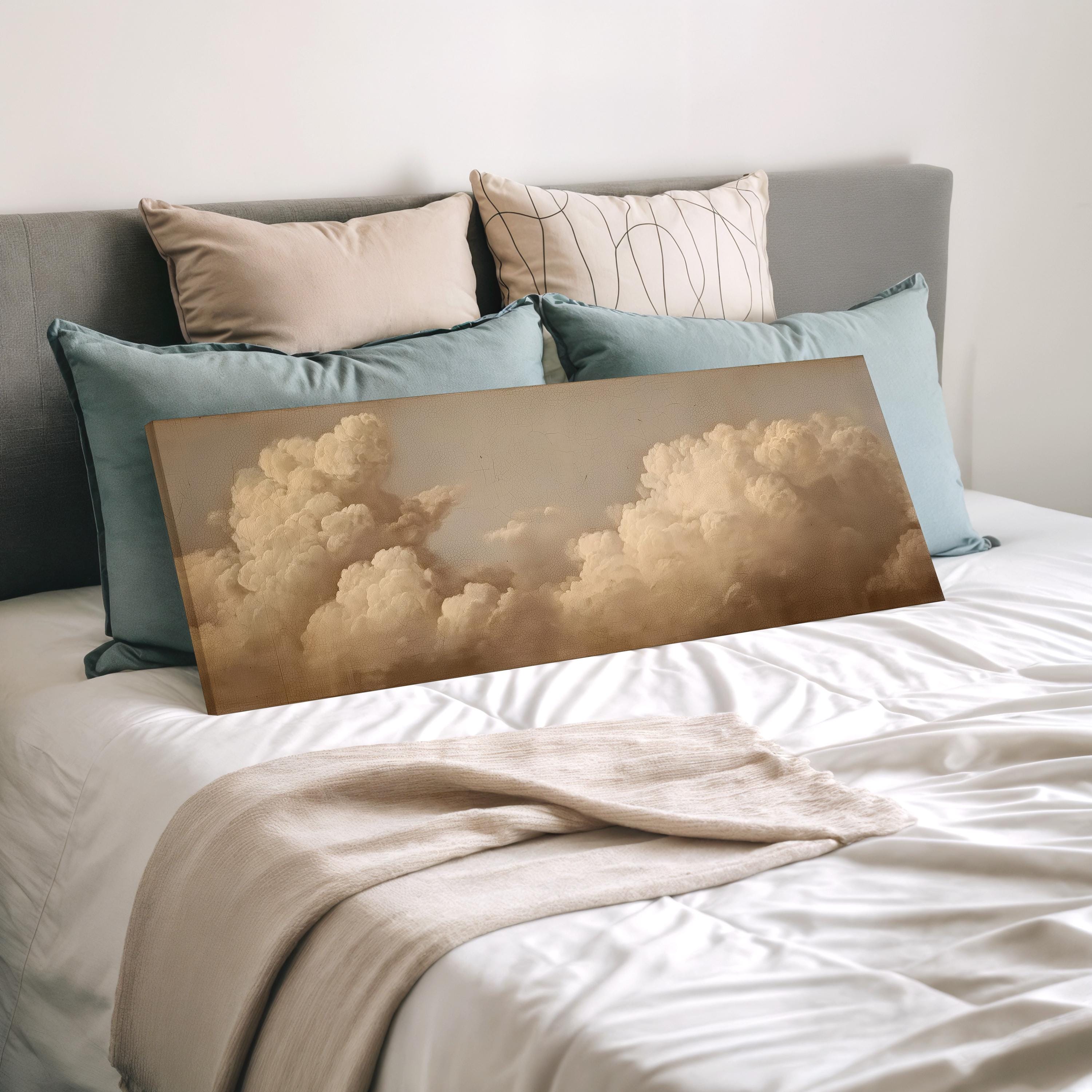 a bedroom with a bed covered in white sheets and a large canvas print of a cloudy sky displayed on the bed.