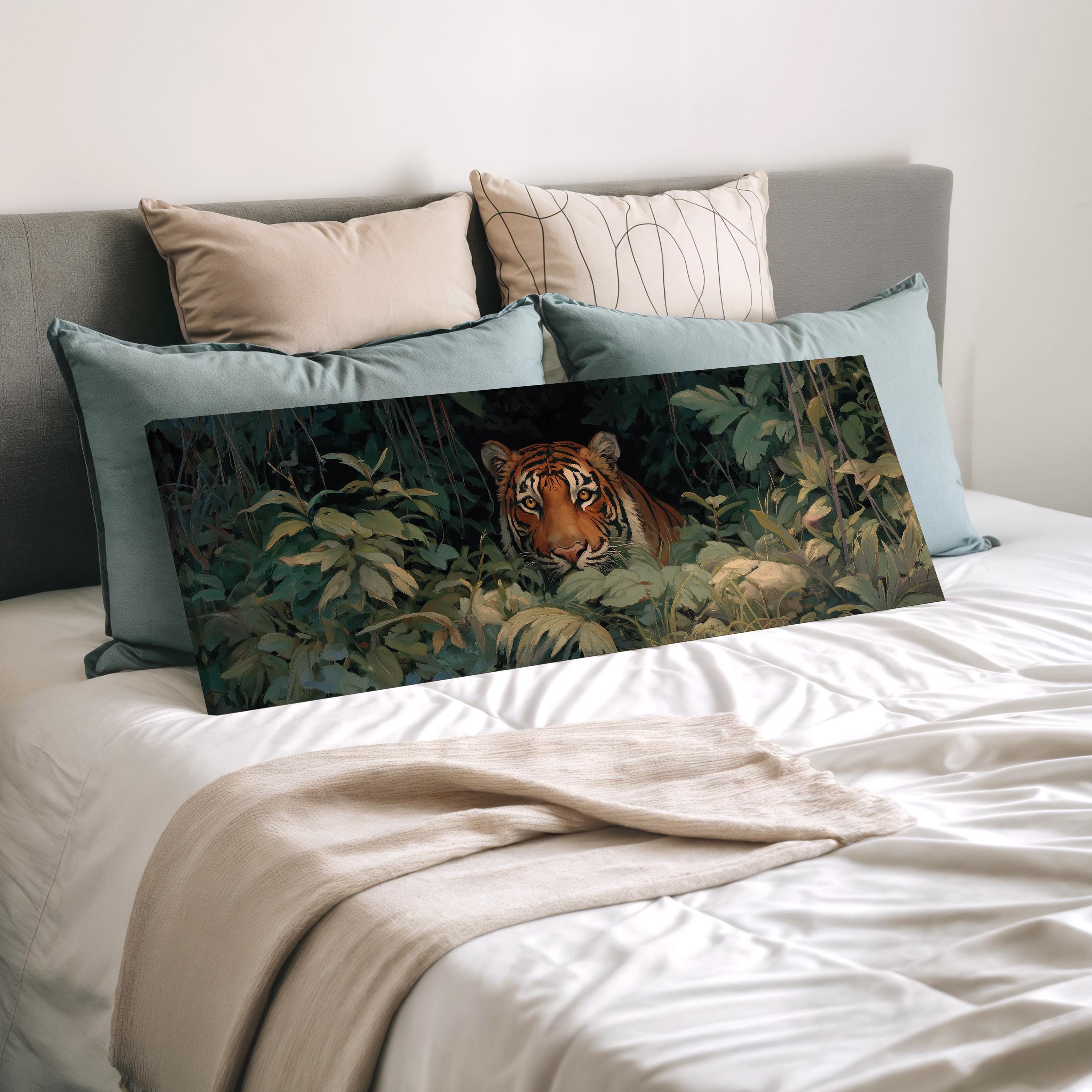 A tiger is peeking out from behind lush green foliage on a bed, surrounded by decorative pillows.